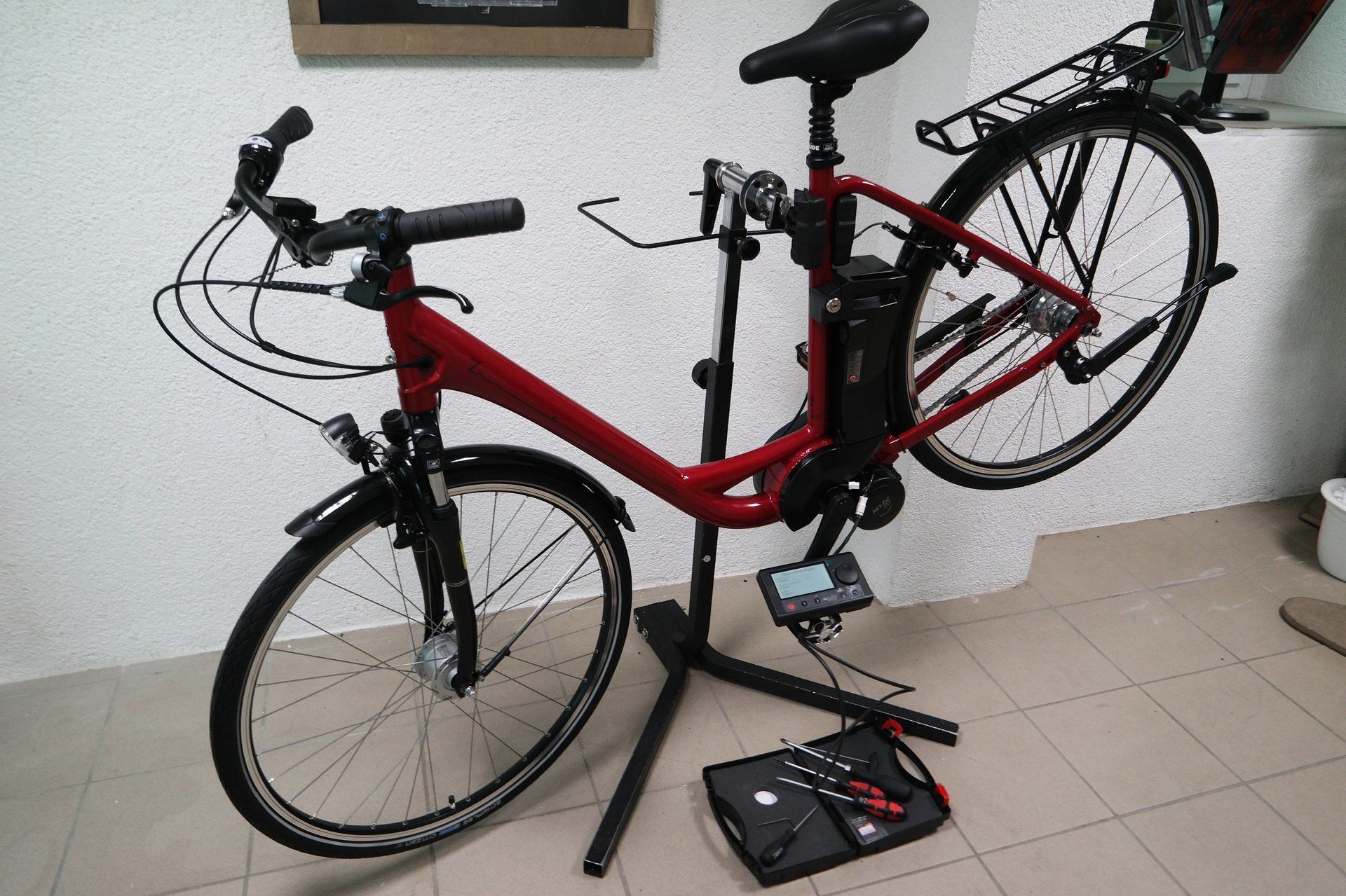 Ein Elektrofahrrad, montiert auf einem Montageständer, daneben ein Diagnosegerät und ein Werkzeugkoffer auf dem Boden.