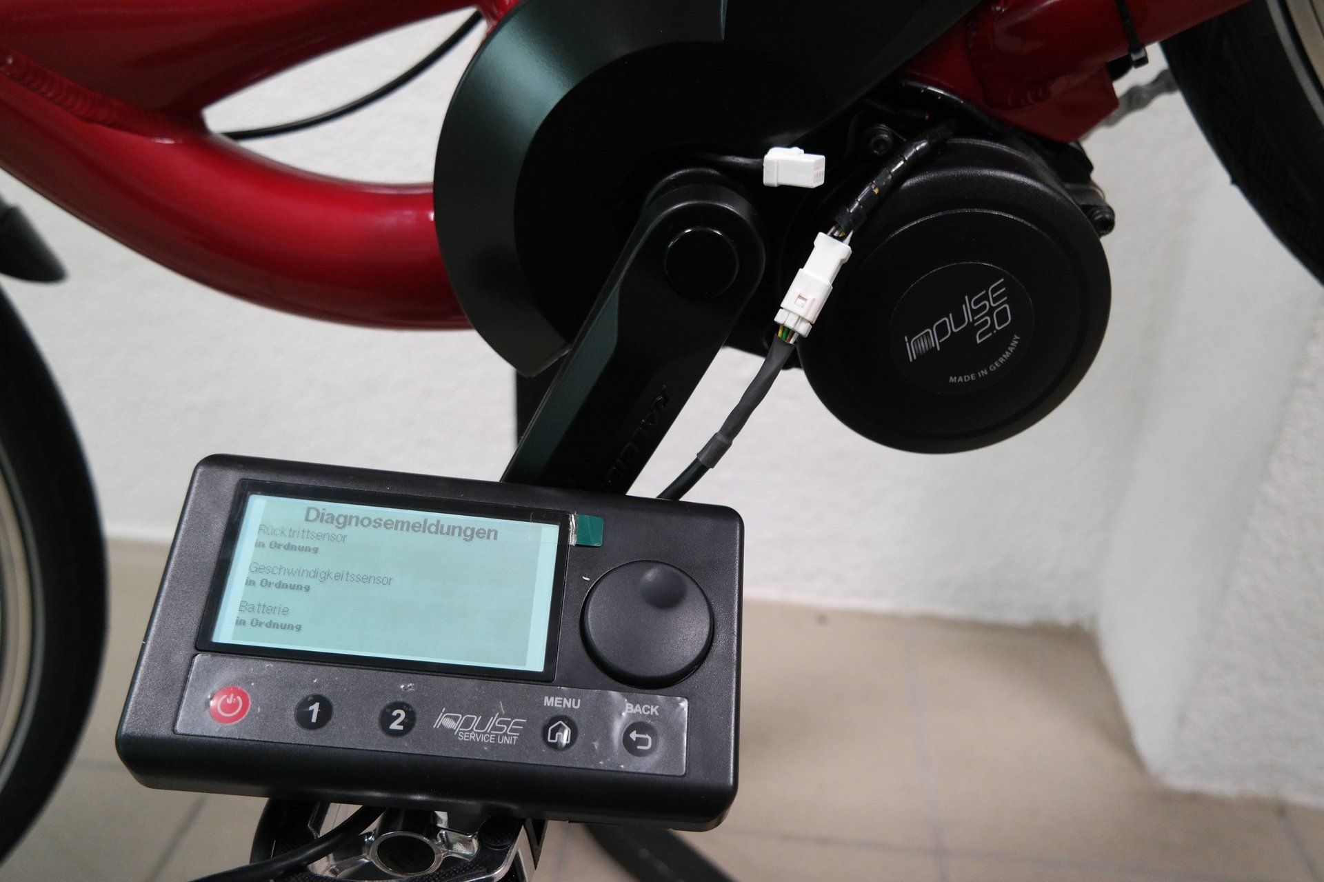 Ein Diagnosegerät mit digitalem Bildschirm, das an einen E-Bike-Motor angeschlossen ist, zur Wartung oder Fehlerbehebung.