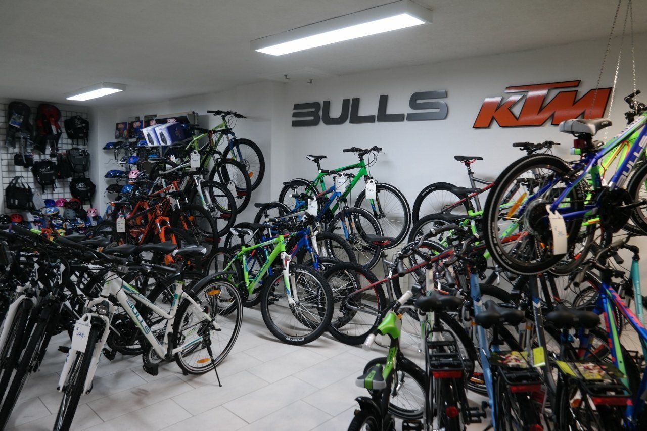 Ein Ladeninterieur, gefüllt mit zahlreichen Mountainbikes und Citybikes, die unter hellem Deckenlicht ausgestellt sind.