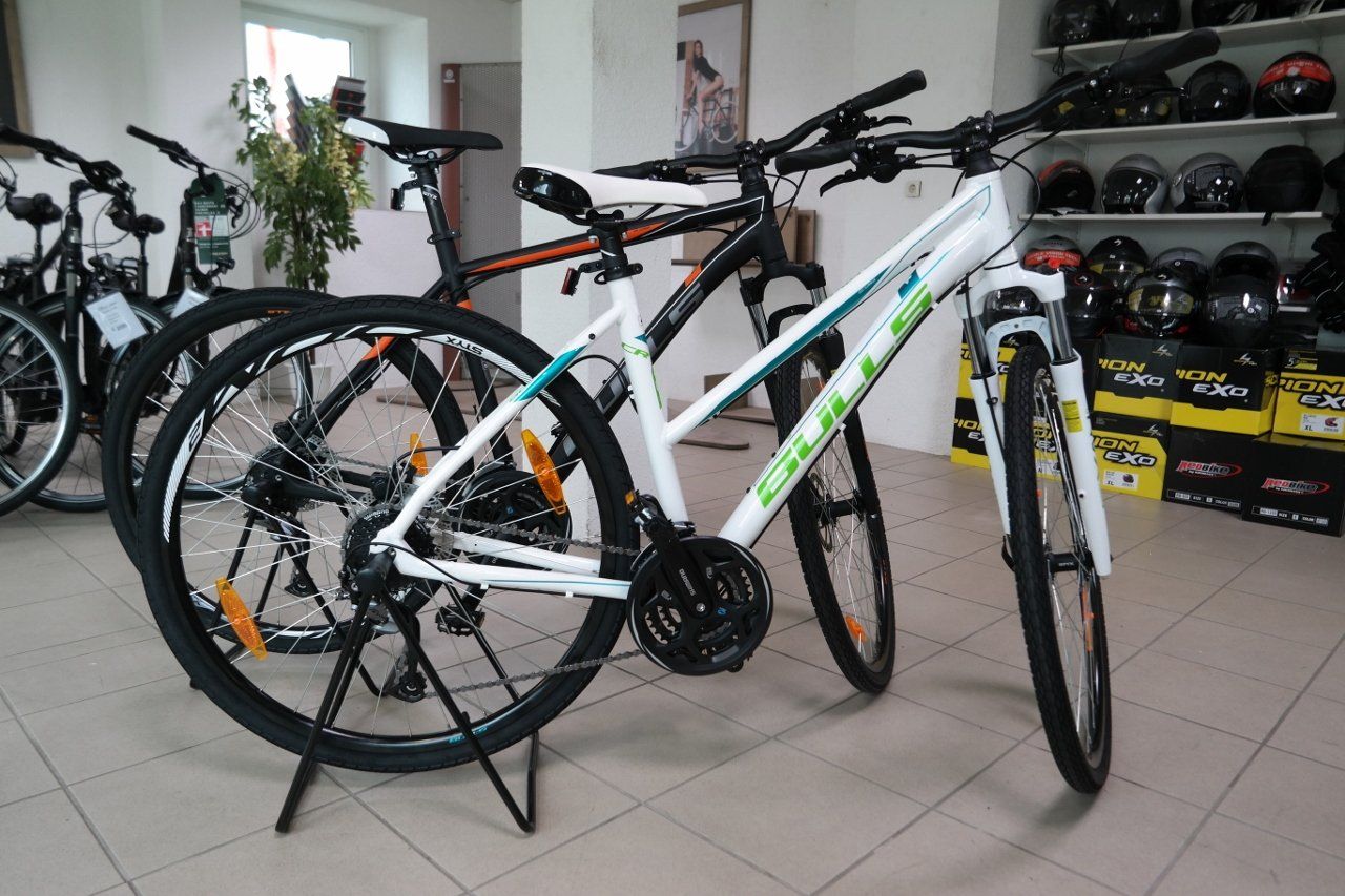 Zwei Mountainbikes, ein weißes und ein schwarzes, stehen in einem hell erleuchteten Fahrradladen.