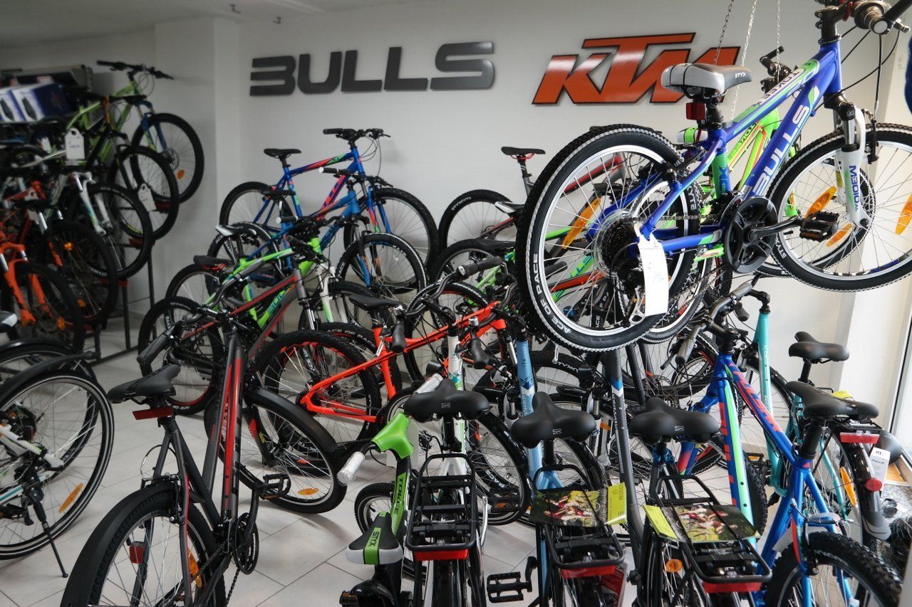 Ein Laden voller Mountainbikes, hinter denen an der weißen Wand die Logos von Bulls und KTM zu sehen sind.