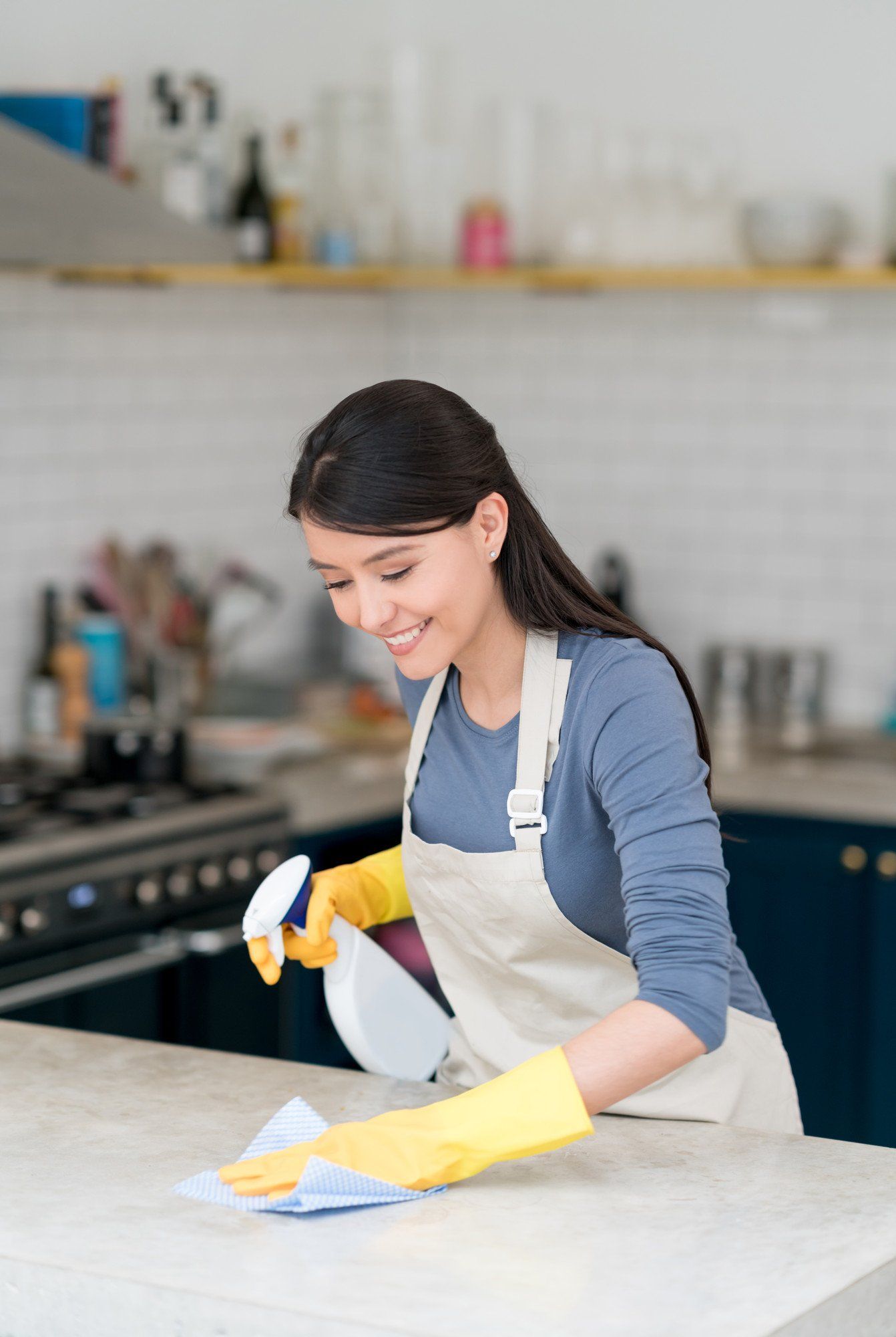 woman wearing gloves and cleaning the kitchen using spray