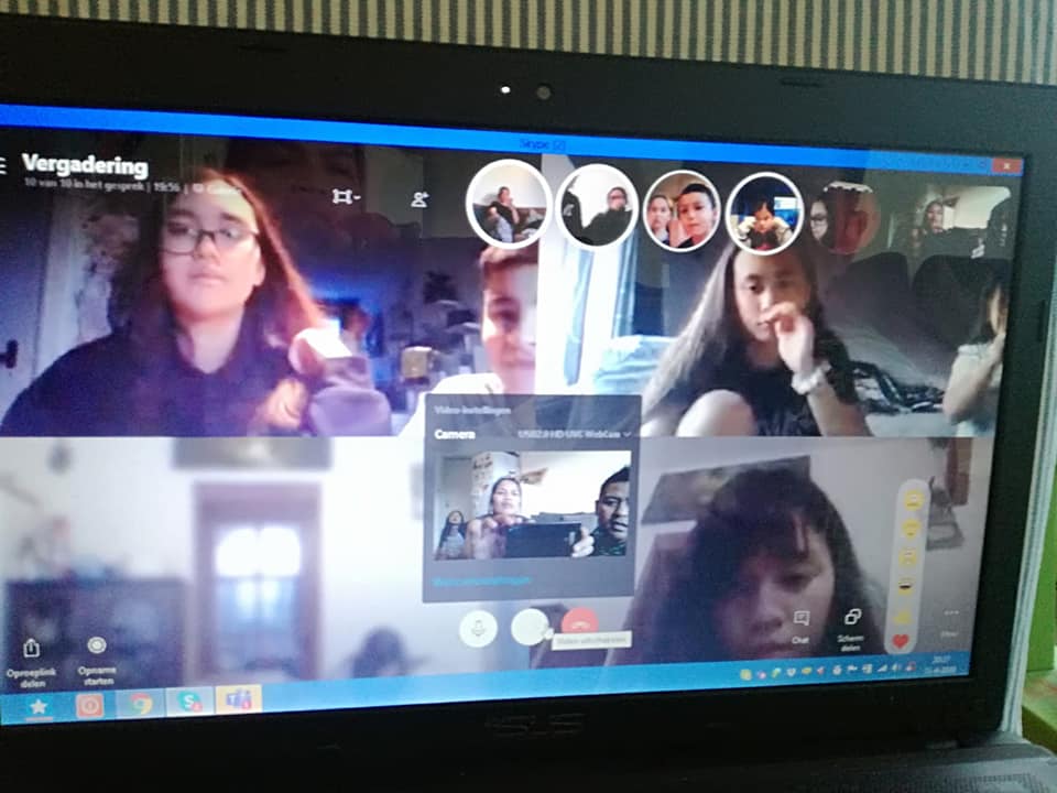 Laptopscherm met een videogesprek. Meerdere mensen in aparte videovensters, sommigen kijken naar de camera.