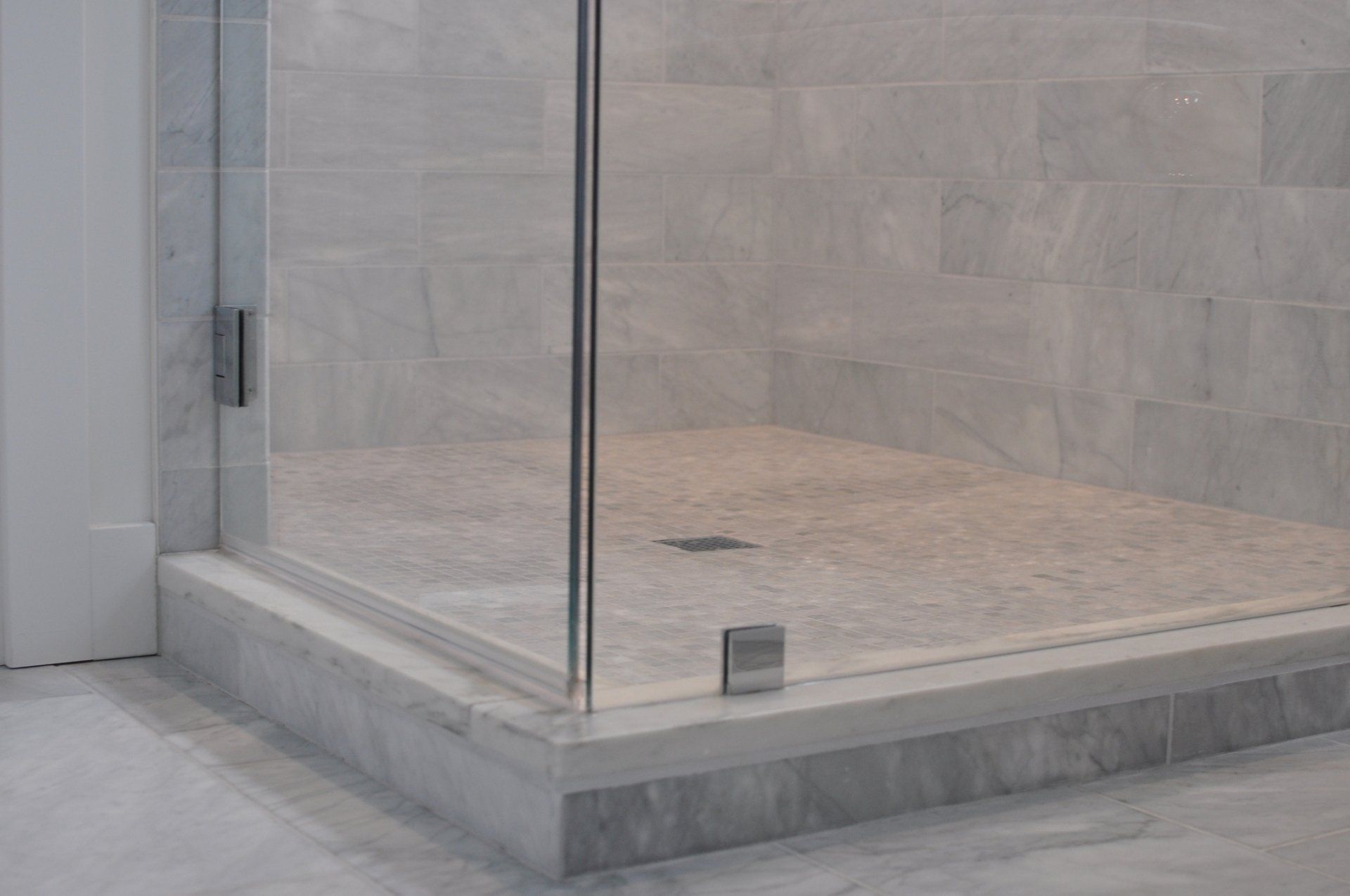 Modern walk-in shower with frameless glass enclosure and marble tile design in luxury bathroom in Louisville, KY.