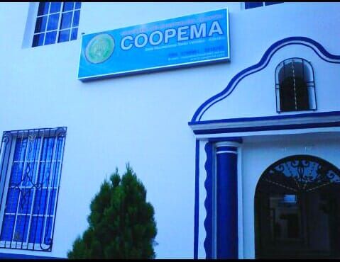 Blue building exterior with a COOPEMA sign, barred windows, and an arched doorway