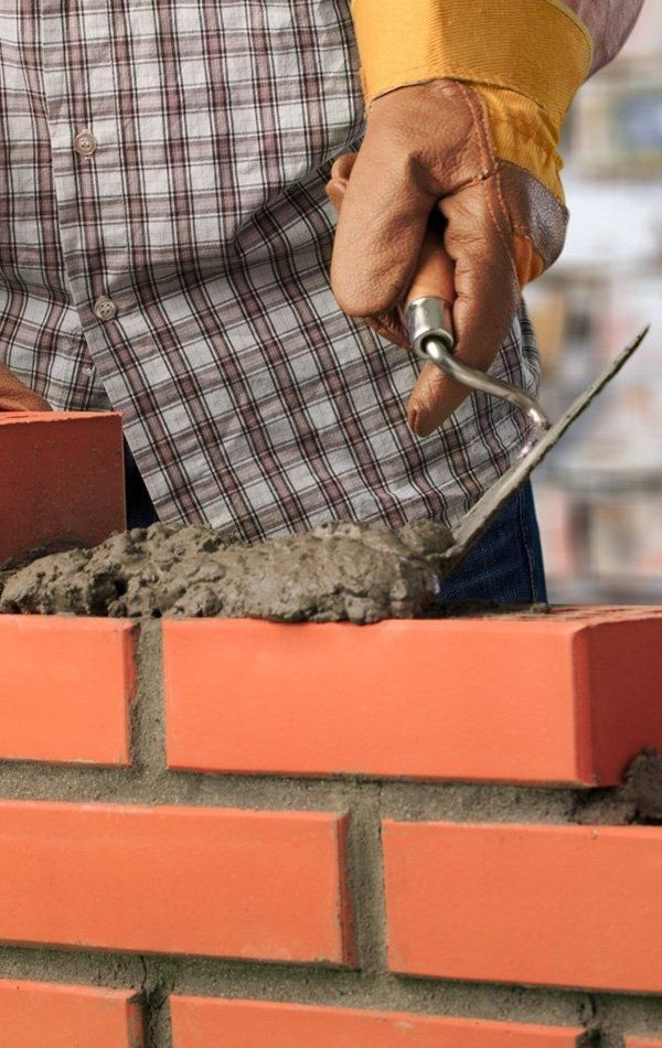 Worker Laying Bricks With Cement — About Us in Yeppoon, QLD