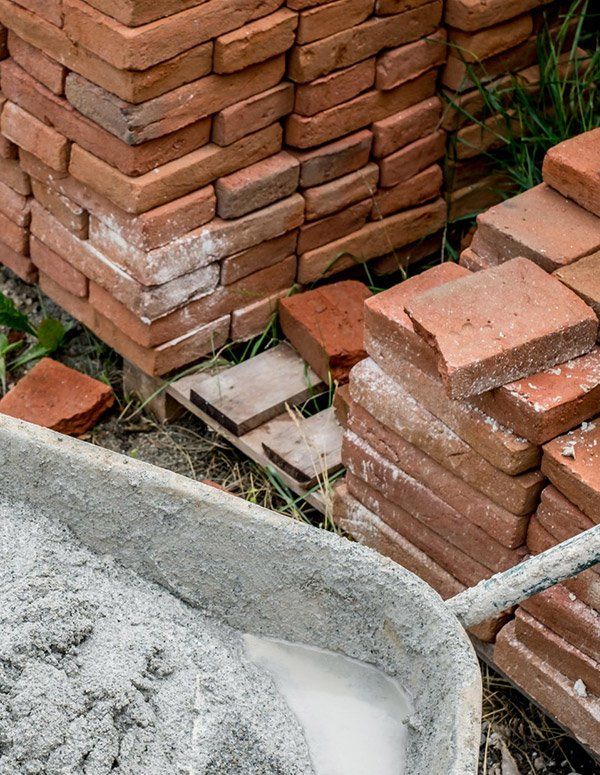 Wheelbarrow With Plaster Next To A Pile Of Bricks — Wheelbarrows in Yeppoon, QLD
