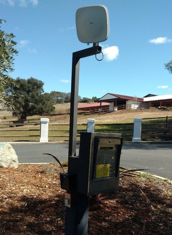 Outdoor Wi-Fi access point on a dark pole, with a mailbox and open grassy area in the background.