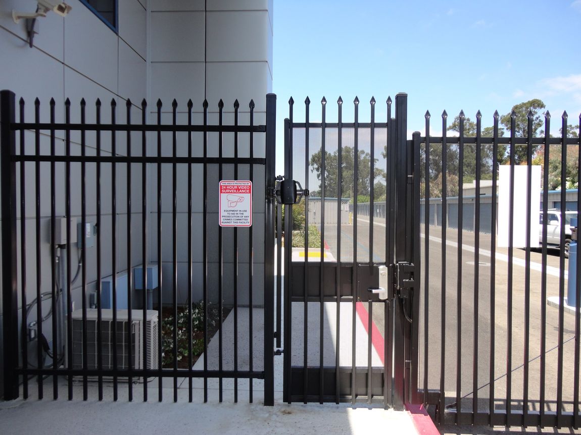 Black metal gate with security signage in front of a building.