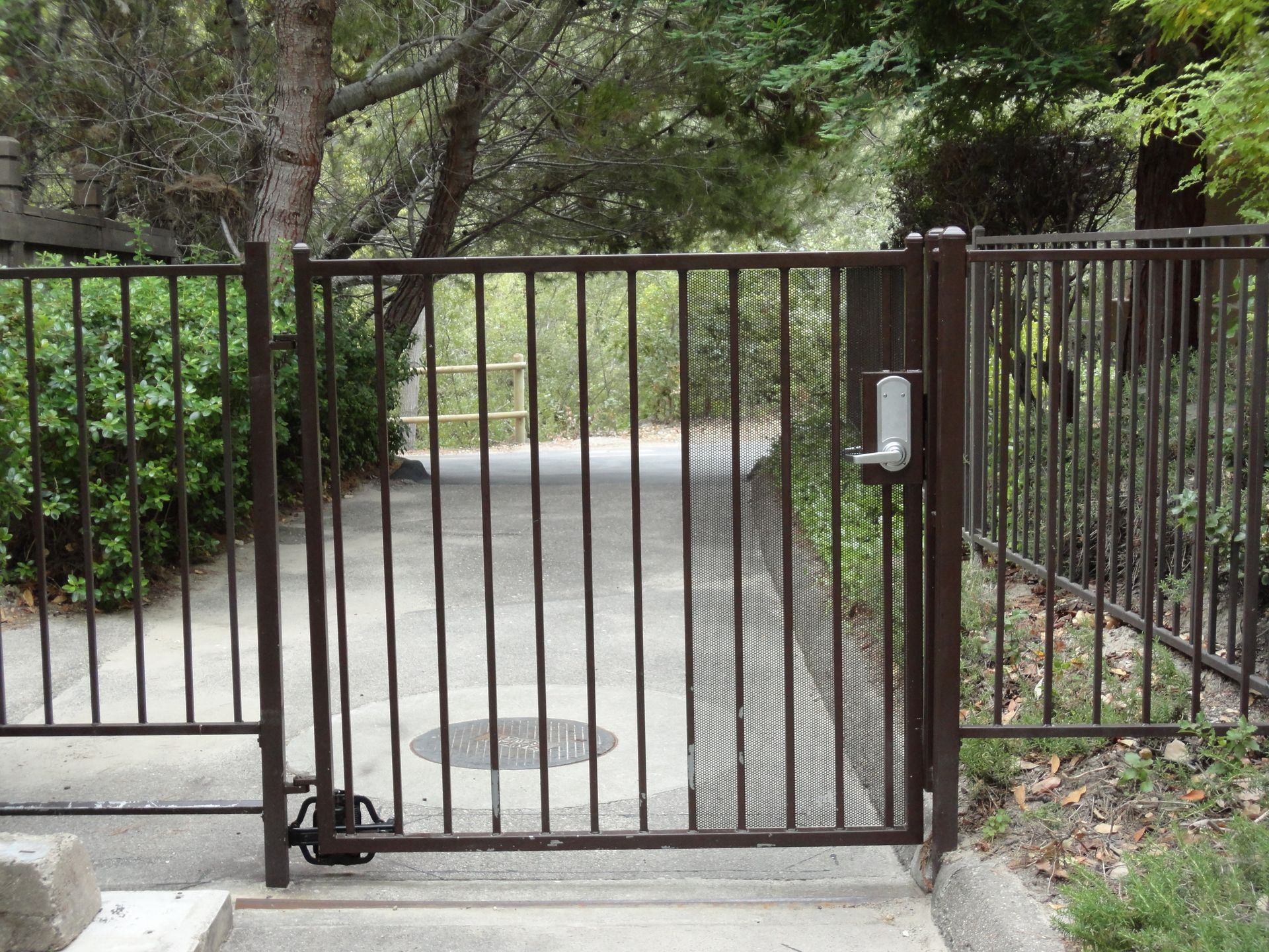 Brown metal gate with vertical bars, and an electronic lock.