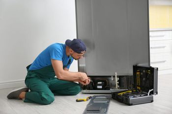 man performing maintenance on a fridge