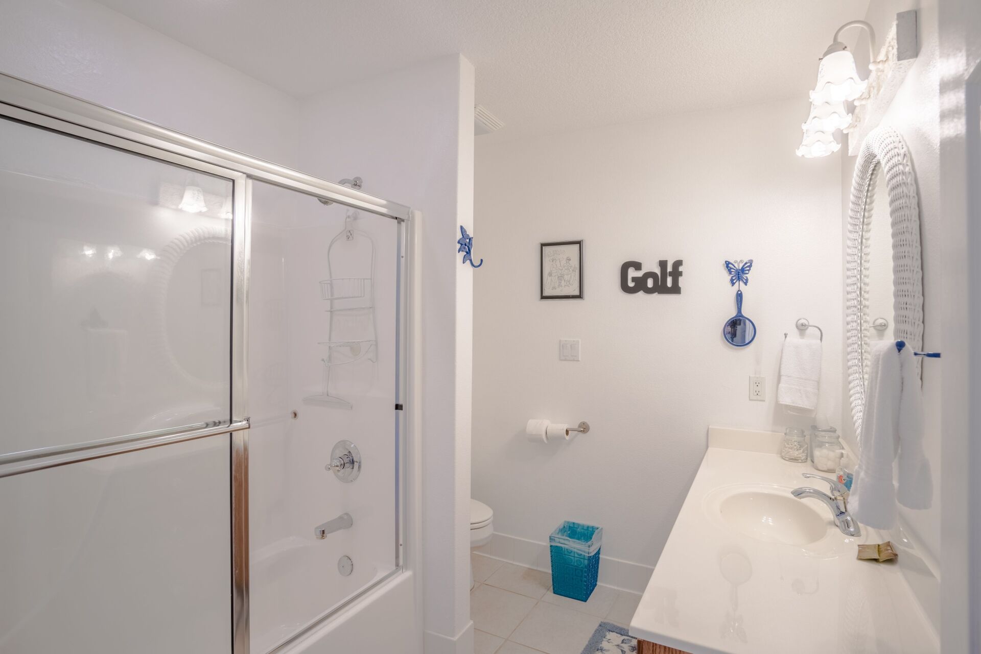 A bathroom with a sink , shower and a sign that says golf on the wall.