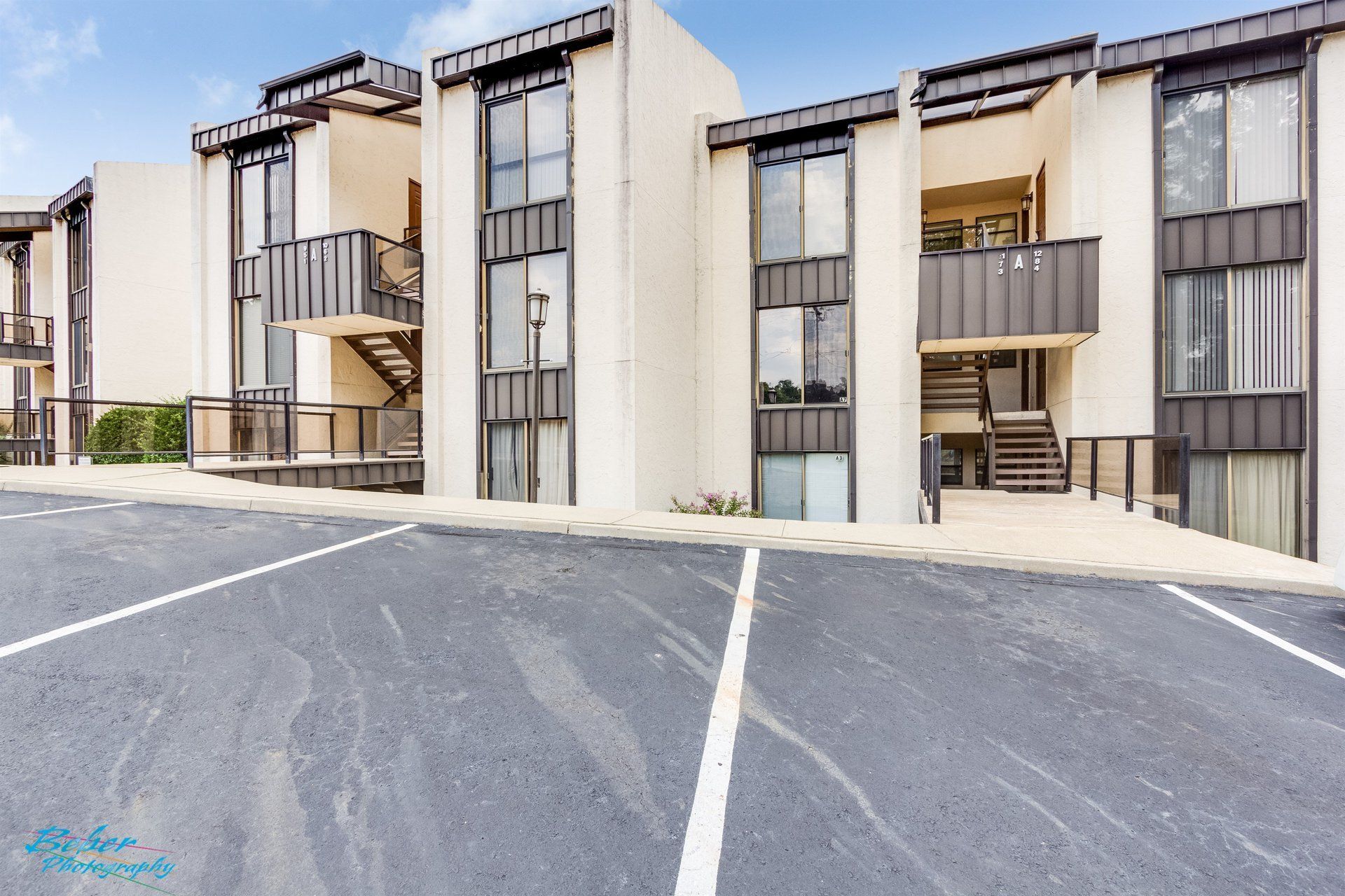 A row of apartment buildings with a parking lot in front of them