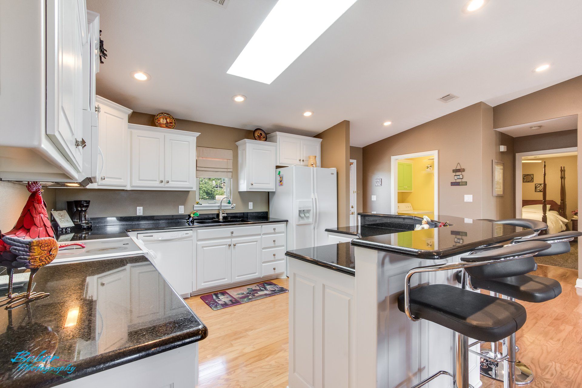 A kitchen with white cabinets and black granite counter tops