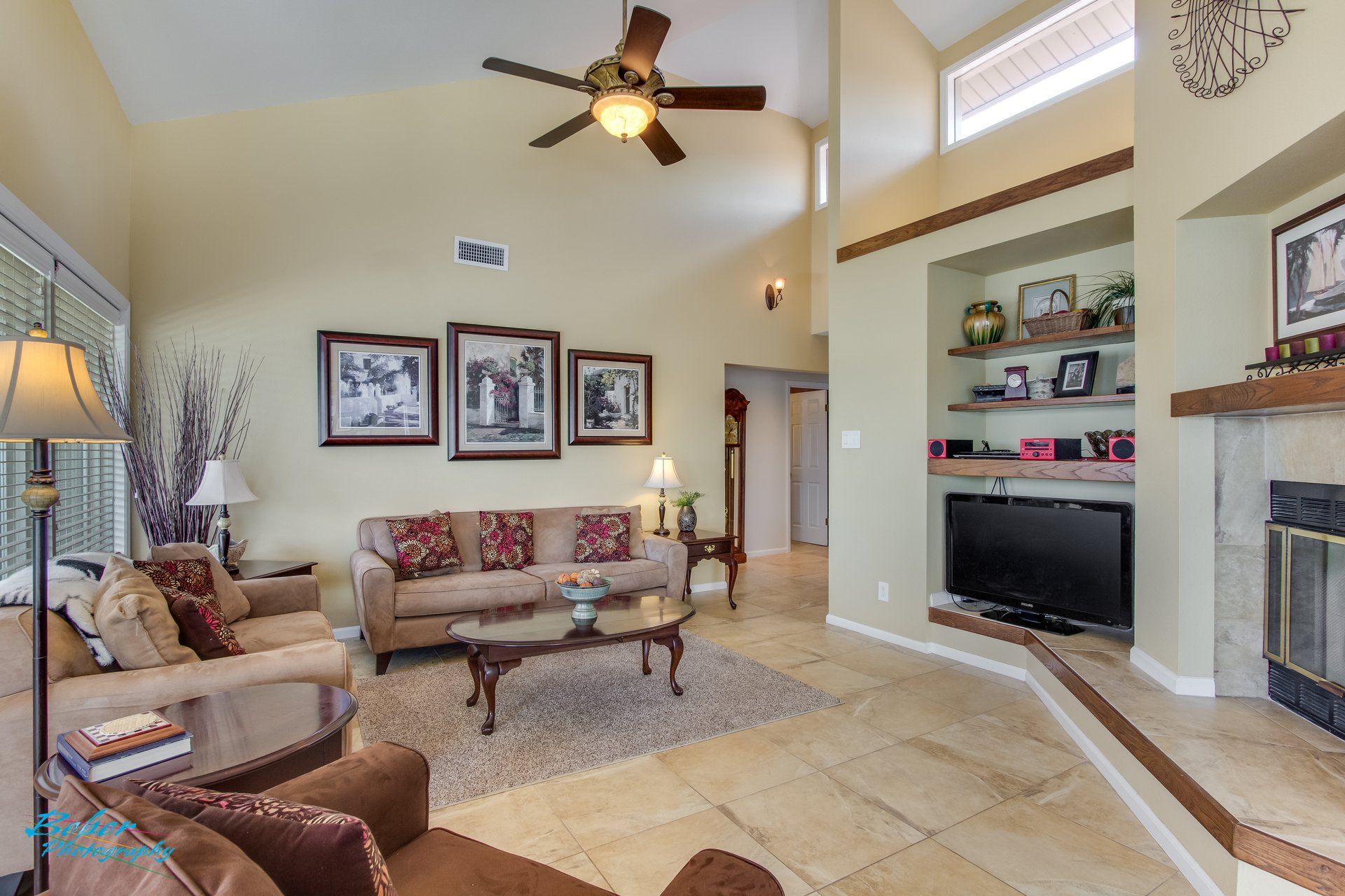 A living room with a ceiling fan and a flat screen tv