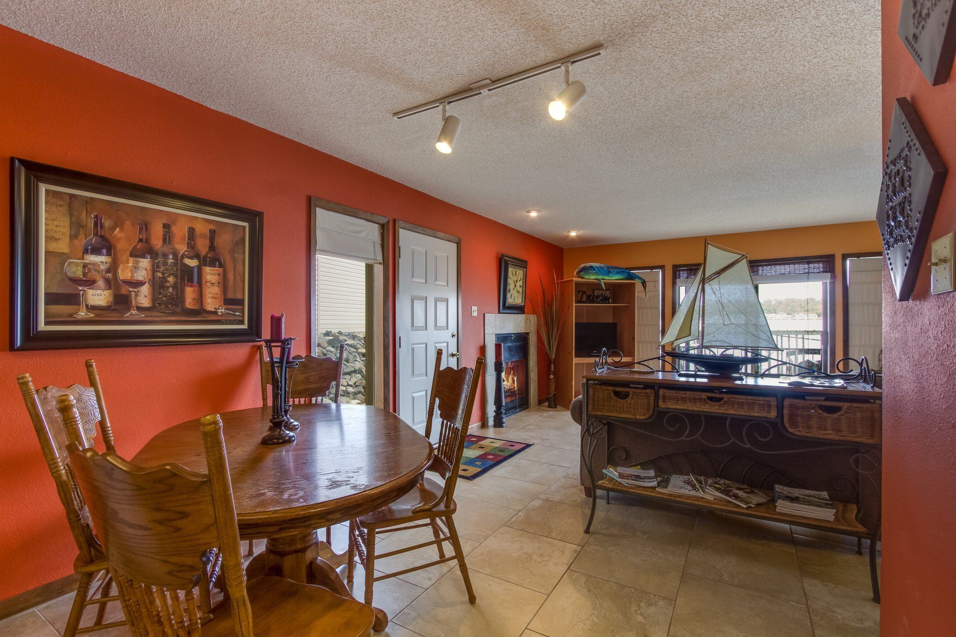A dining room with a table and chairs and a painting on the wall.