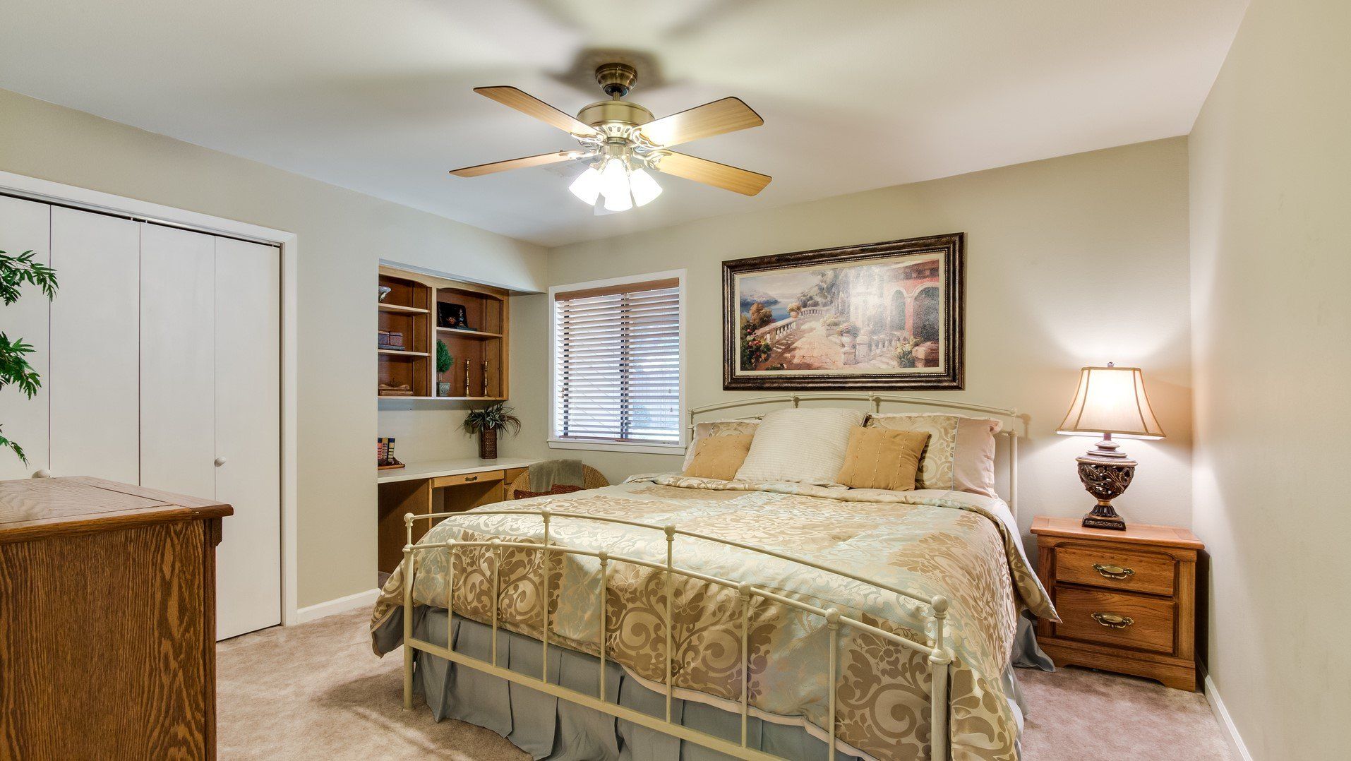A bedroom with a bed , nightstand , dresser and ceiling fan.