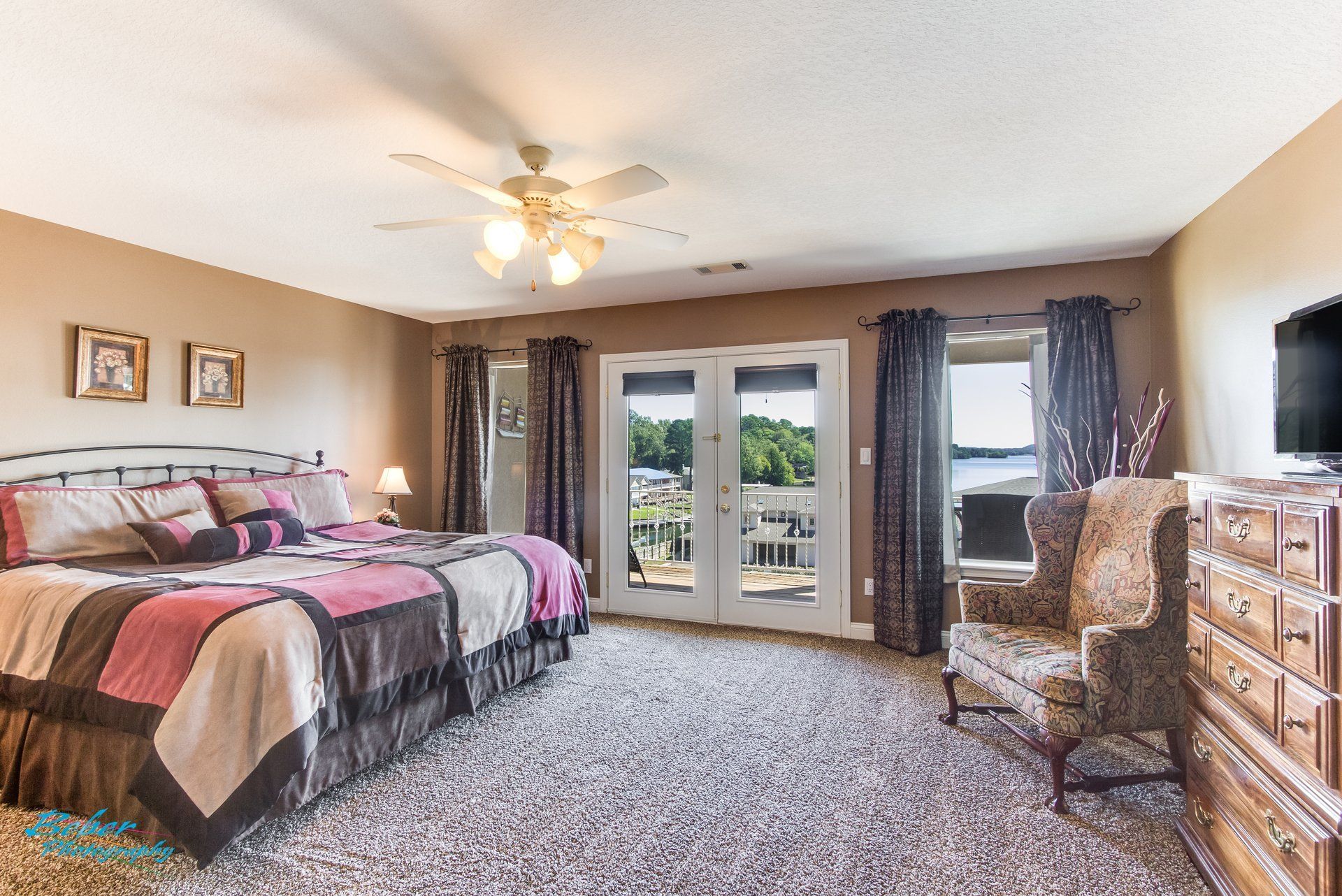 A large bedroom with a king size bed , chair , dresser and television.