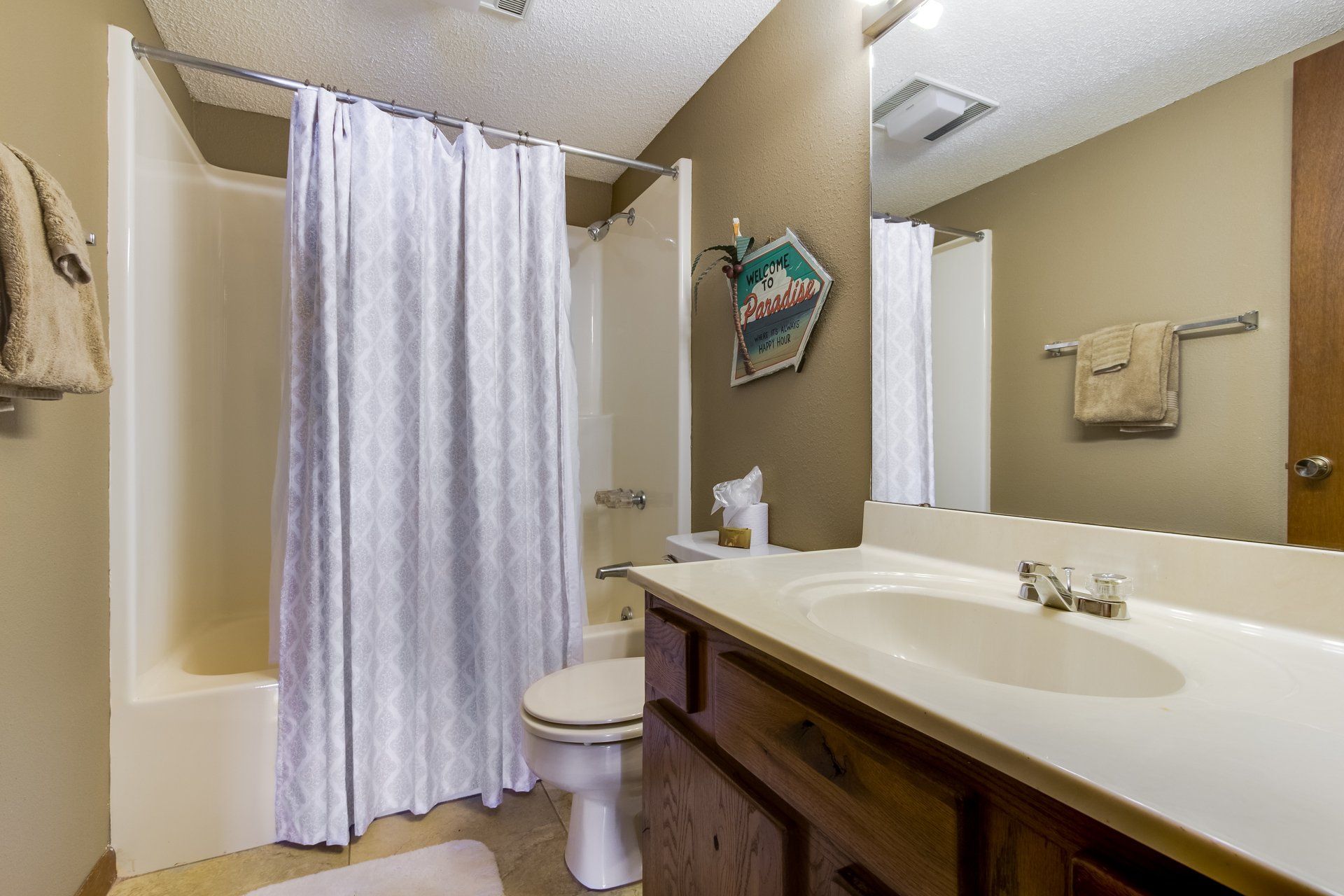 A bathroom with a toilet , sink , shower and mirror.
