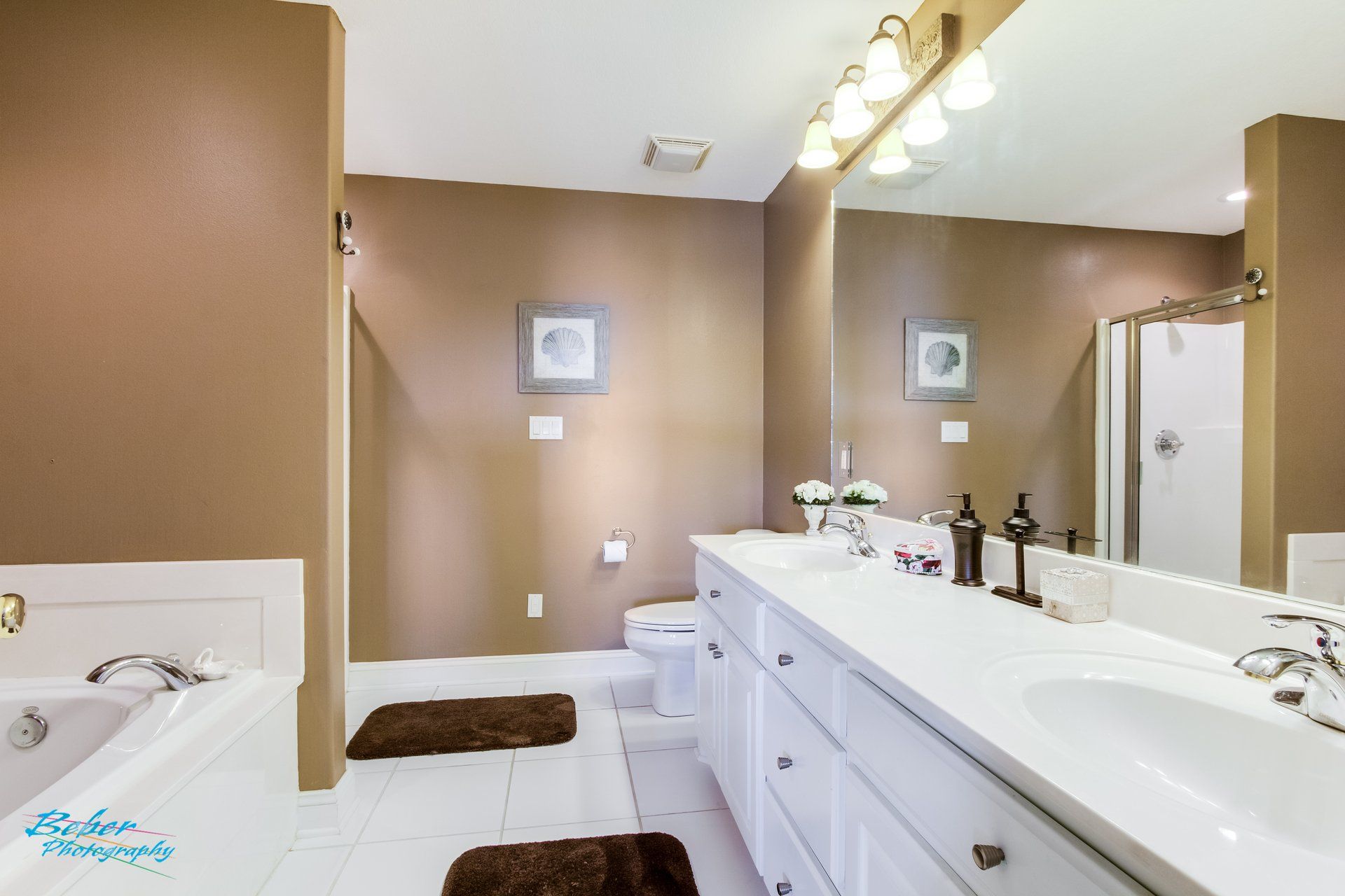 A bathroom with two sinks , a tub , and a large mirror.
