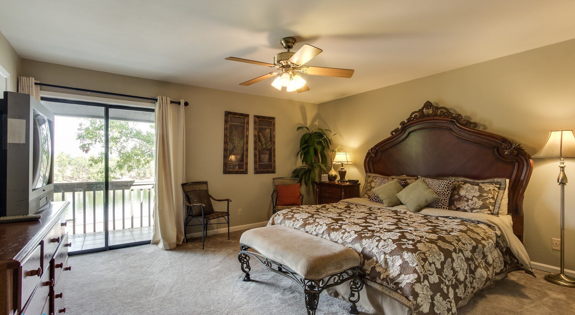 A bedroom with a large bed and a ceiling fan