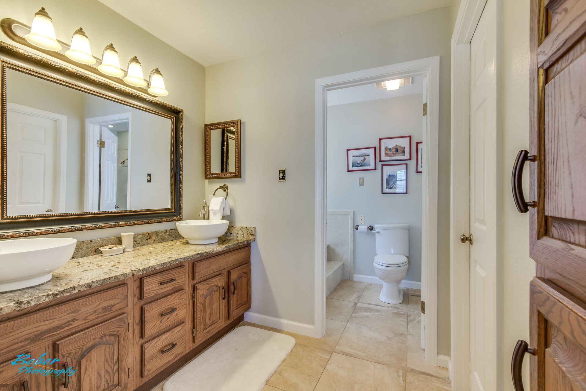 A bathroom with two sinks , a mirror and a toilet.