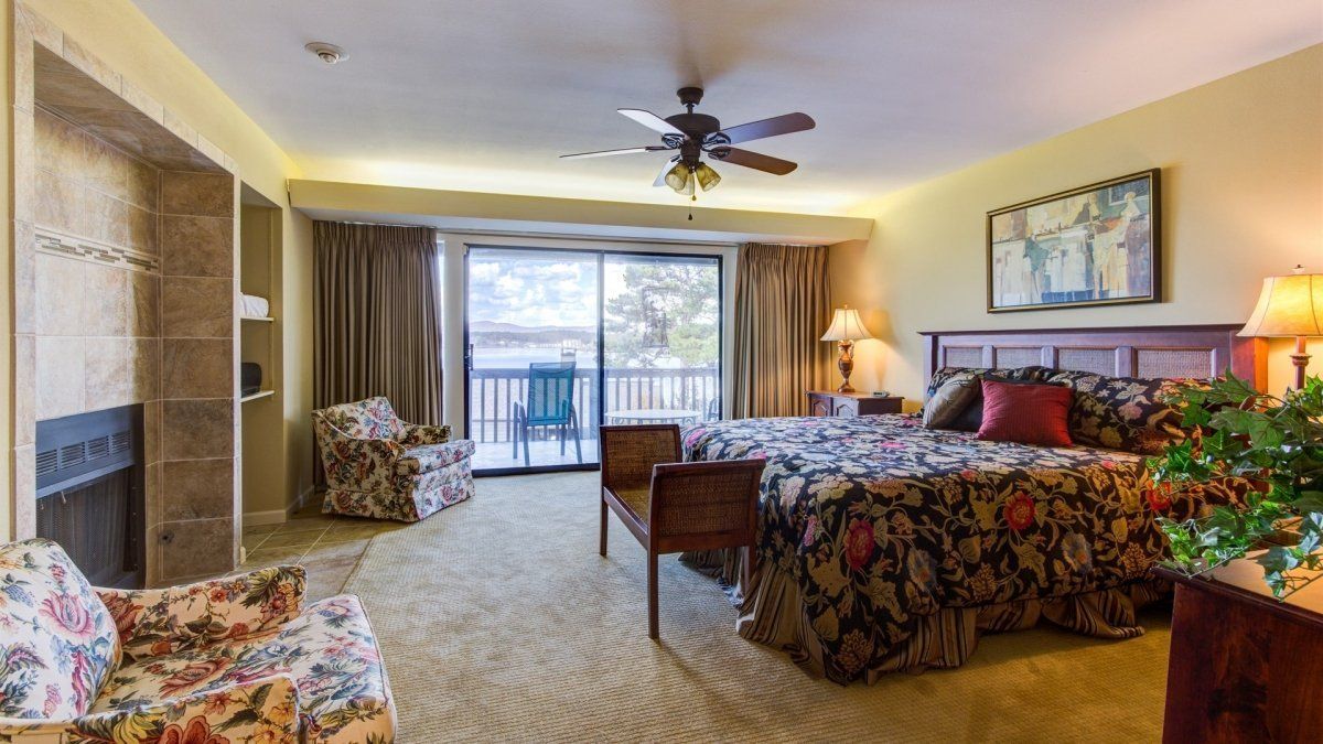 A hotel room with two beds , a fireplace and a balcony.
