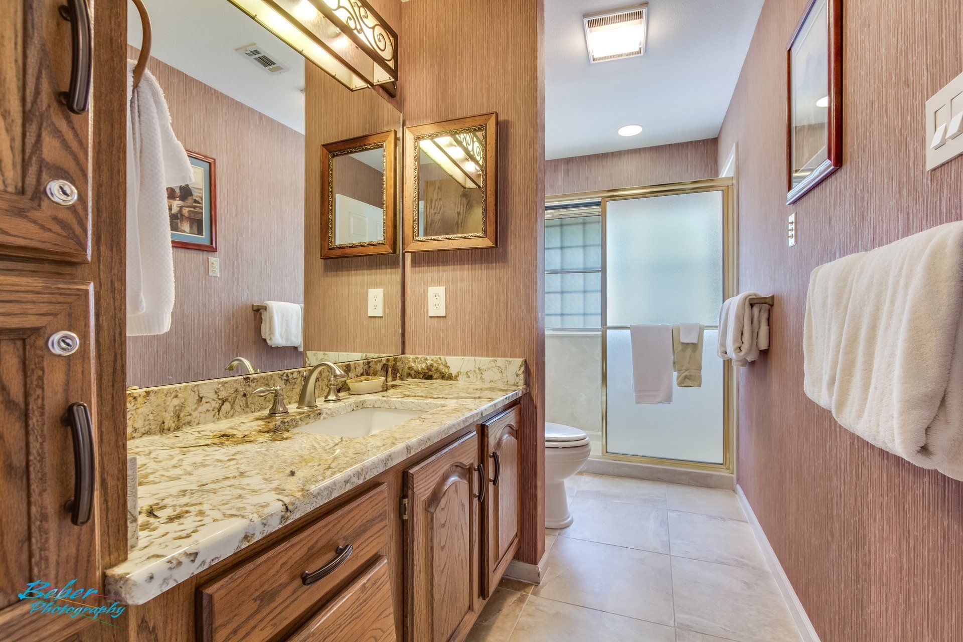 A bathroom with two sinks , a toilet , and a walk in shower.