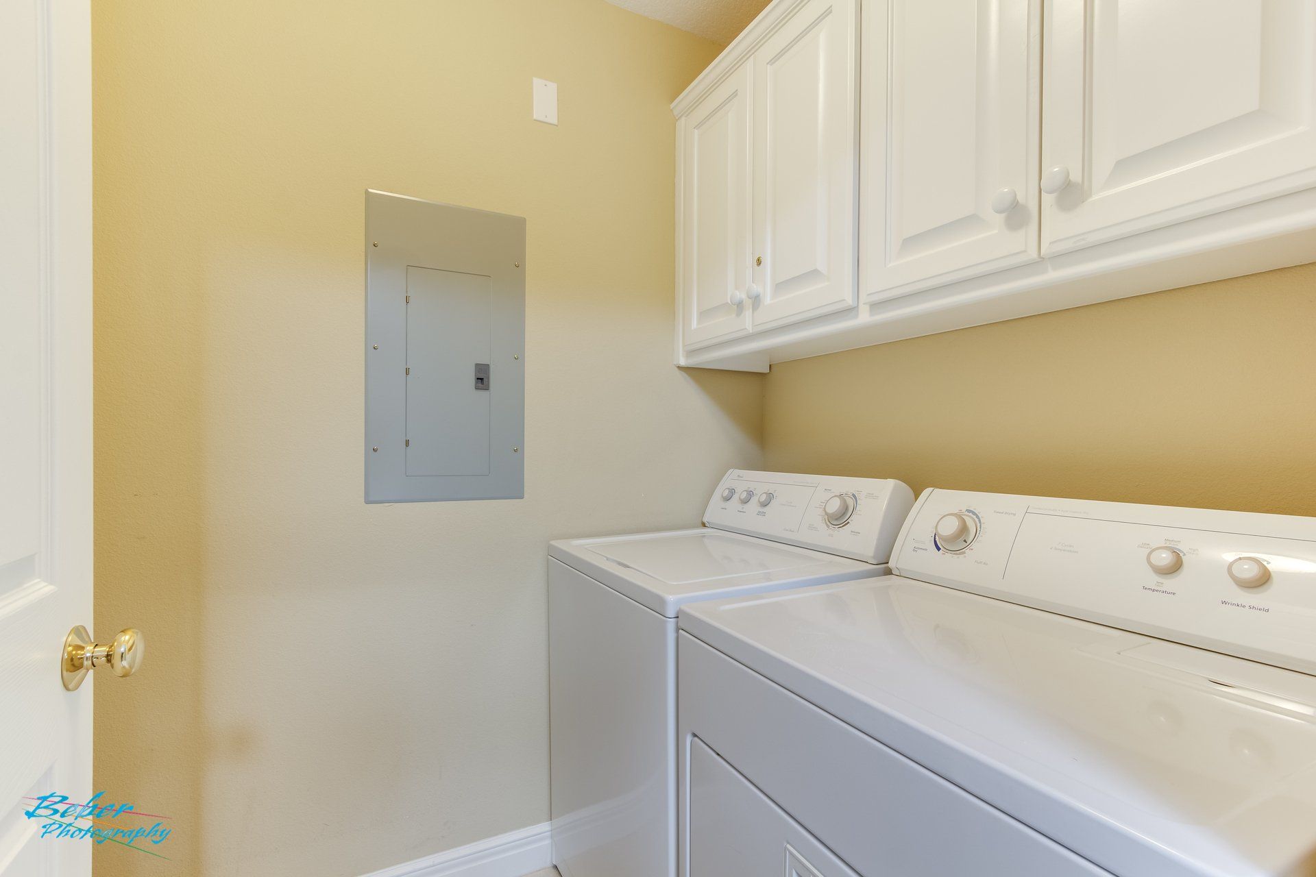 A laundry room with a washer and dryer and a mirror.