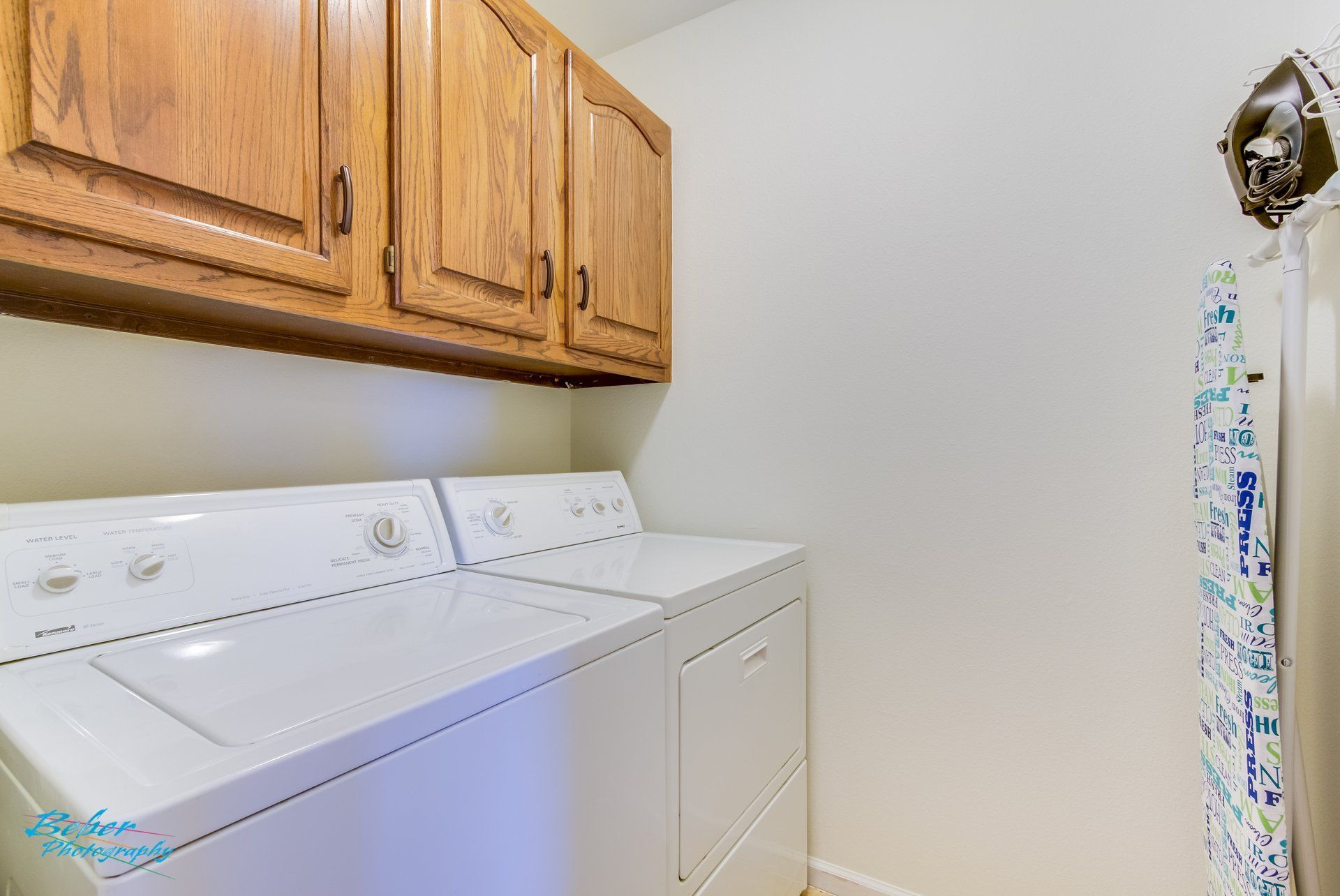 A laundry room with a washer and dryer and wooden cabinets.