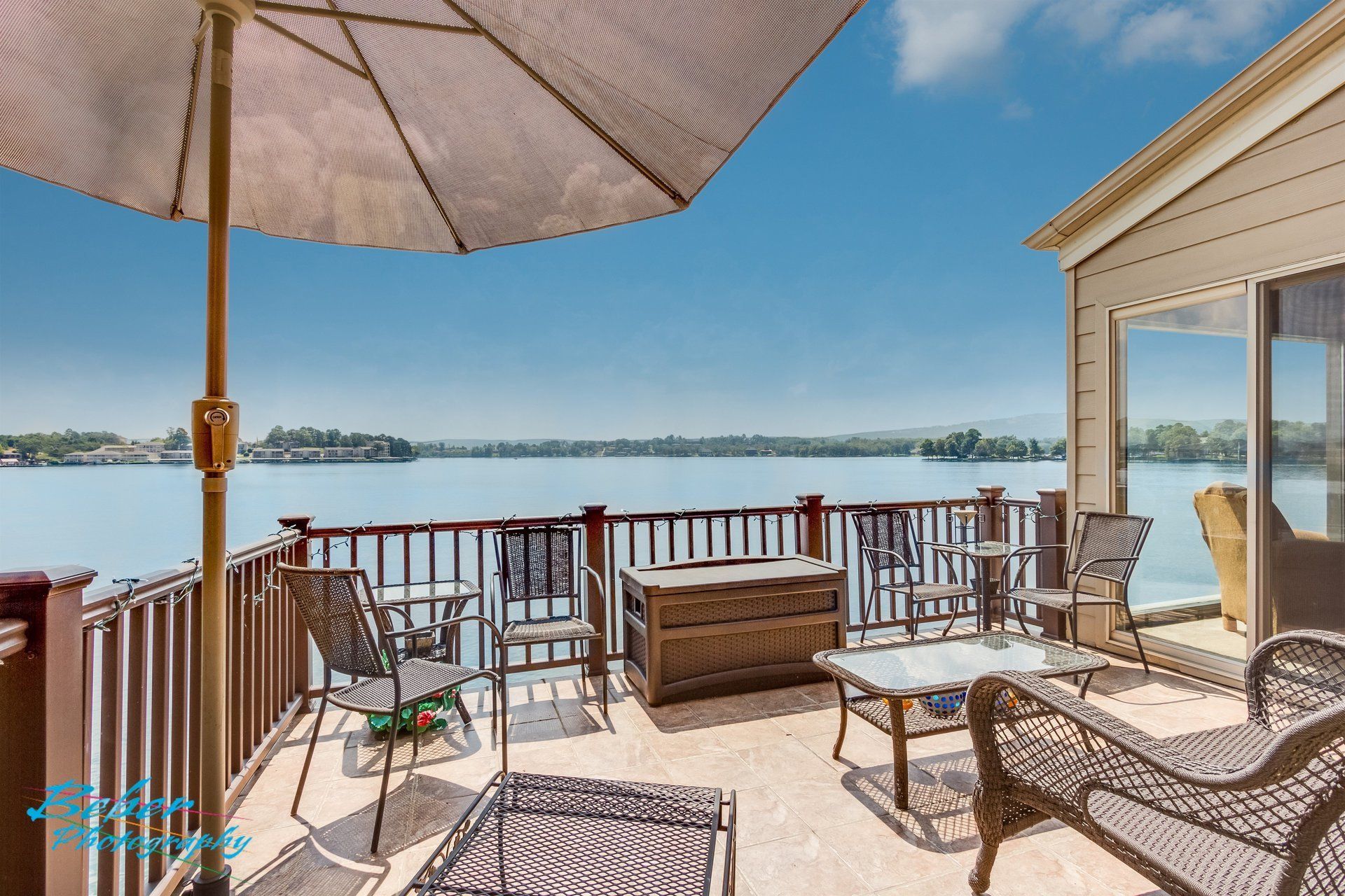 A patio with a view of a lake and an umbrella