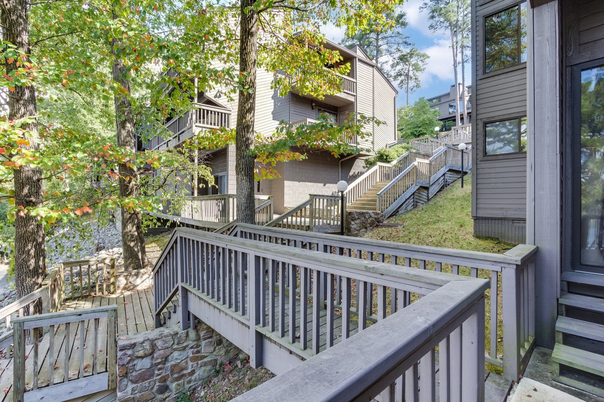 A wooden deck with stairs leading up to a house surrounded by trees.