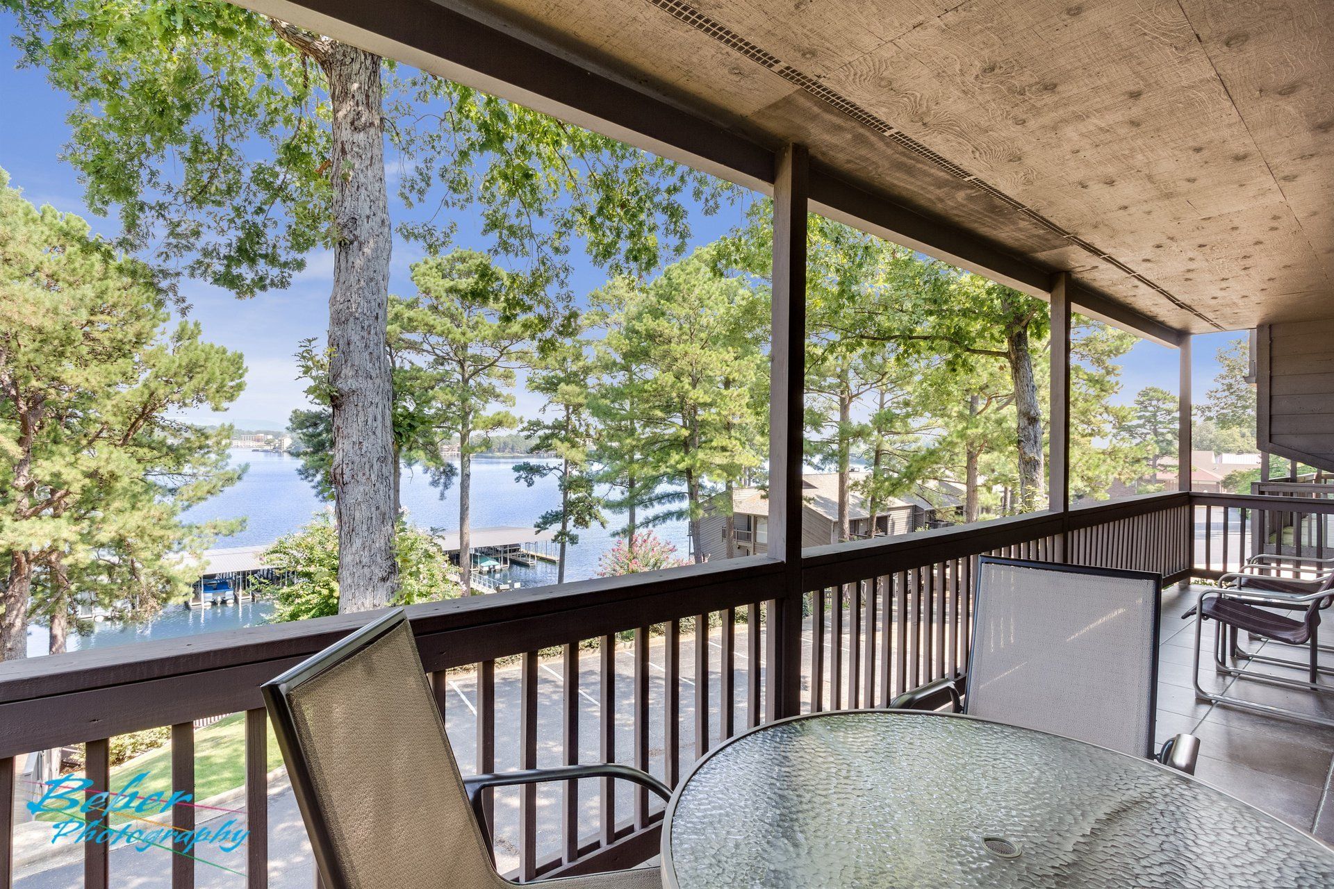A screened in porch with a table and chairs overlooking a lake.