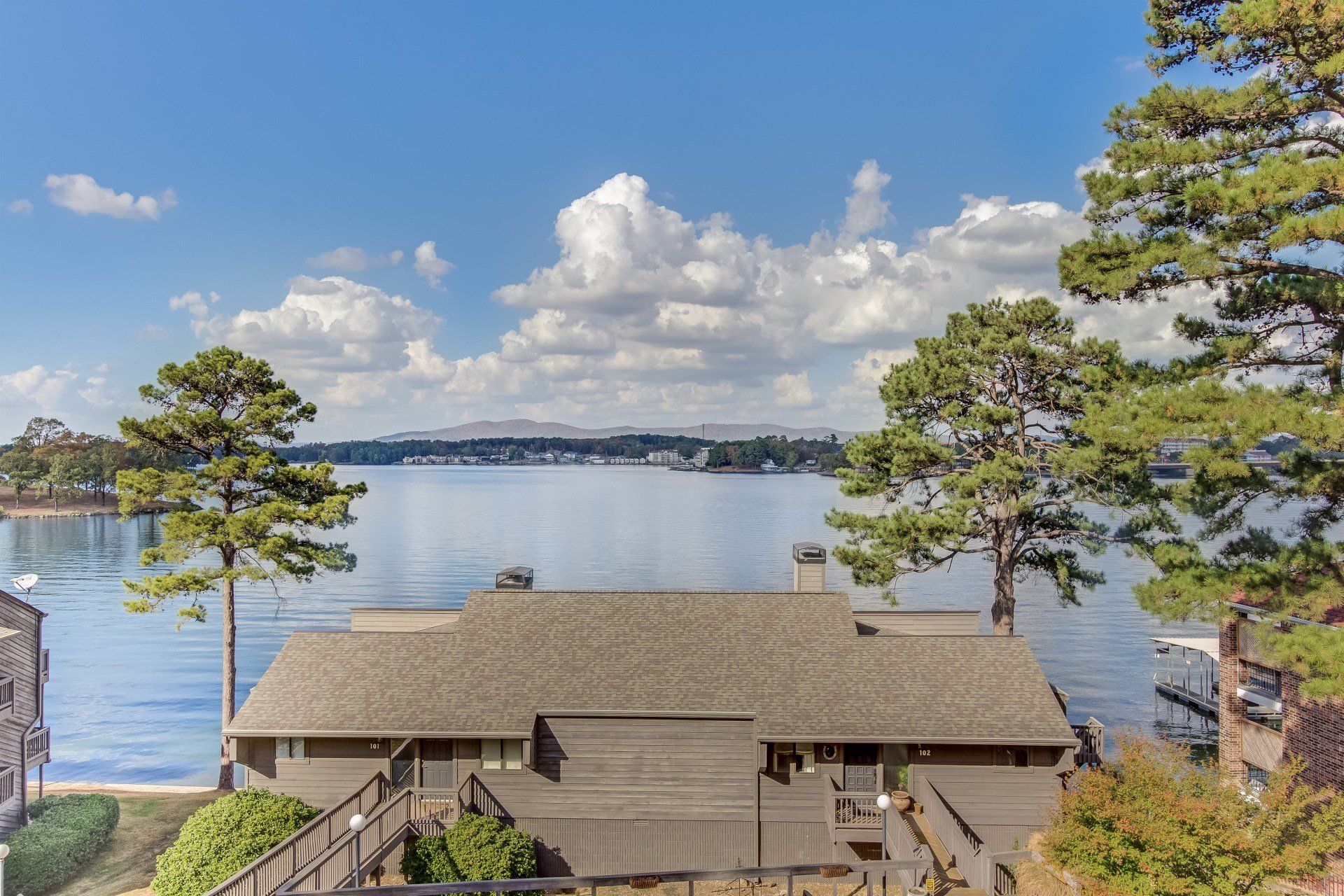 A house is sitting on the shore of a lake surrounded by trees.