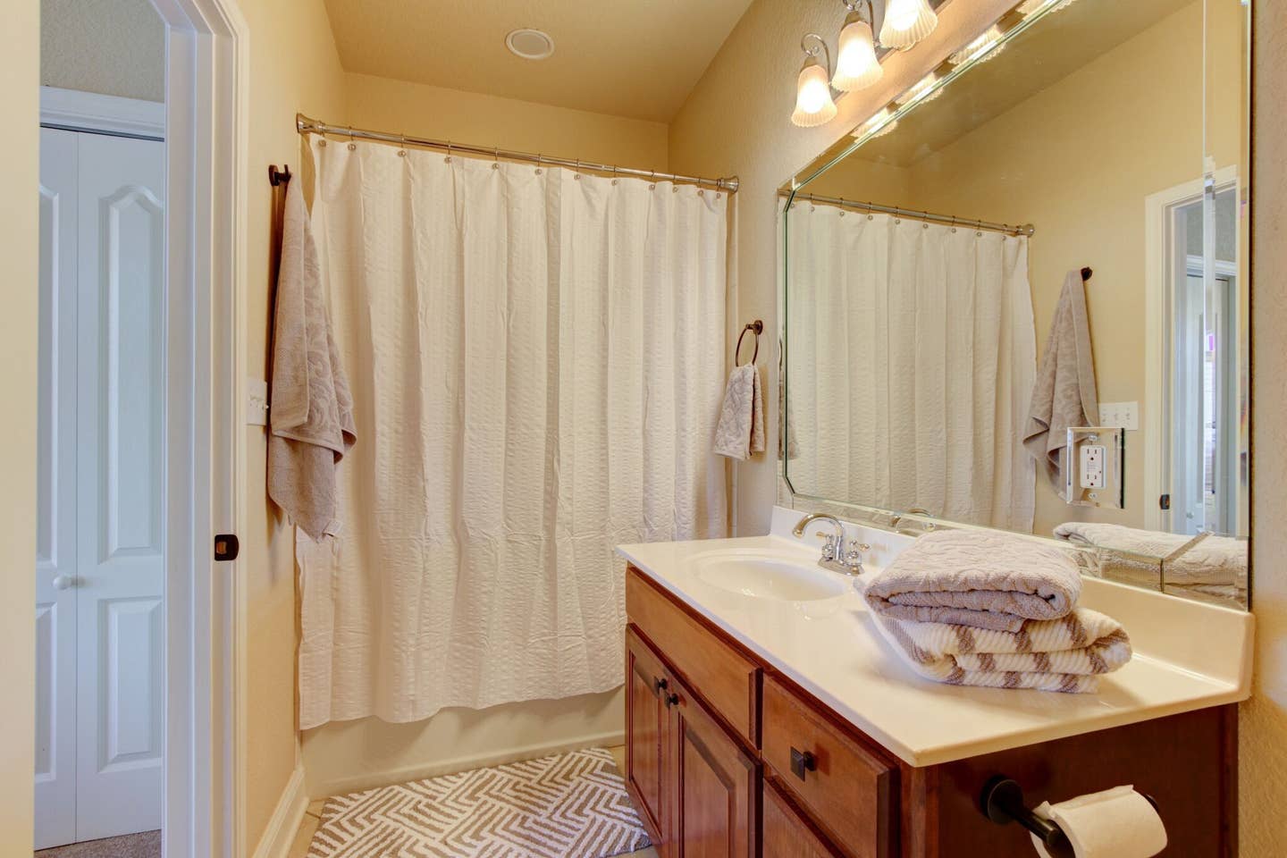 A bathroom with a sink , mirror and shower curtain.
