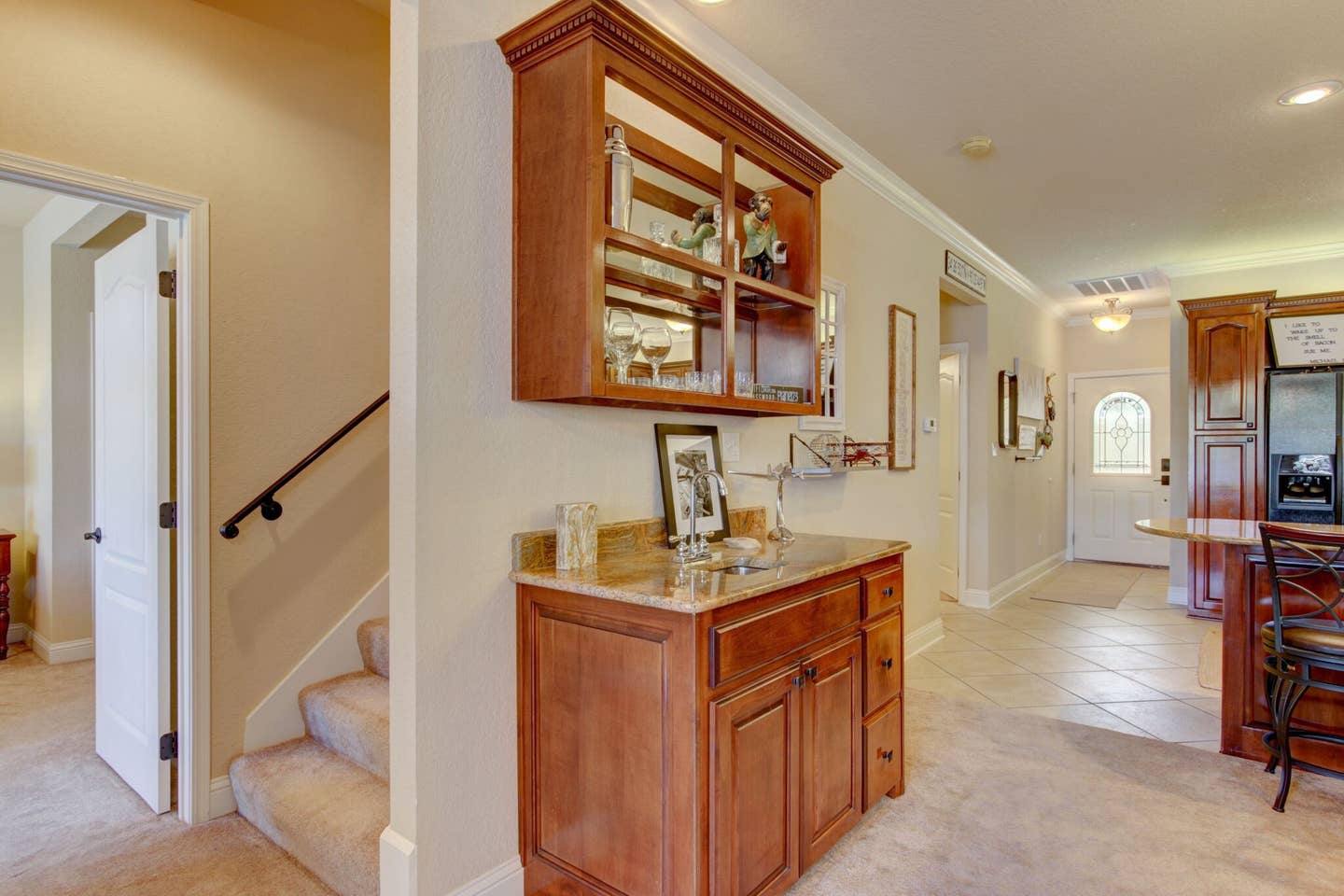 A hallway in a house with a staircase and a wooden cabinet.