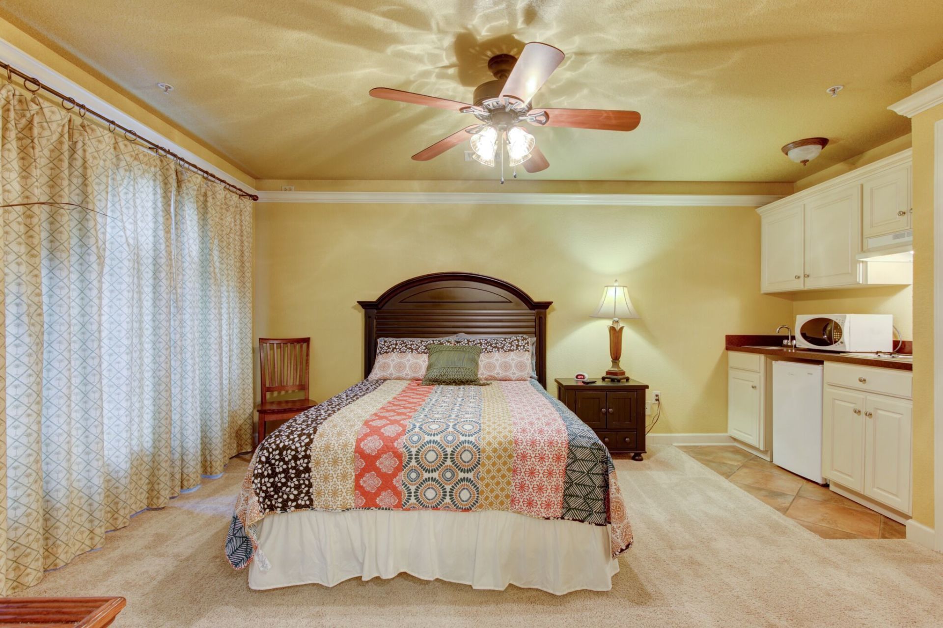 A bedroom with a large bed and a ceiling fan