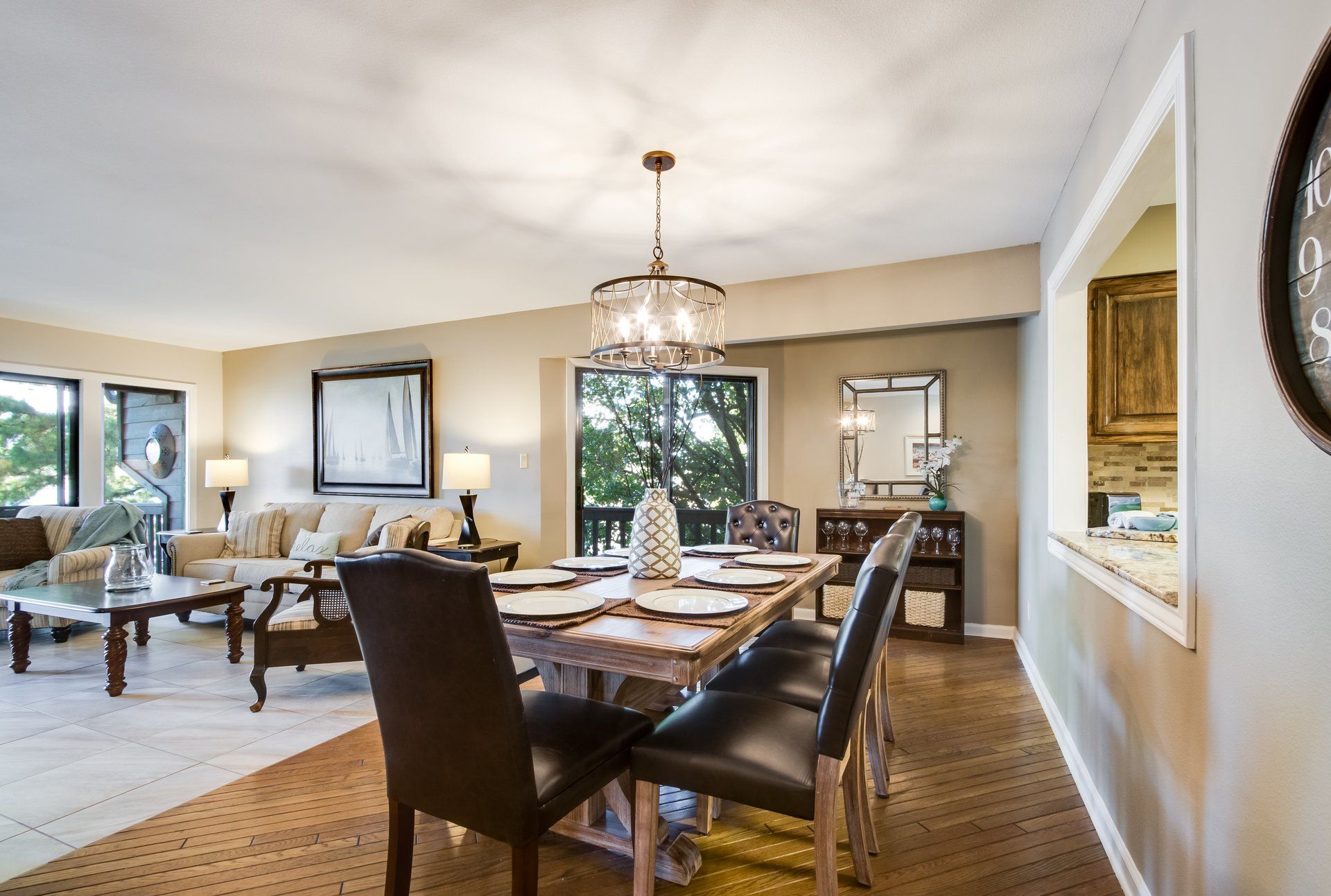 A living room with a dining table and chairs and a clock on the wall.