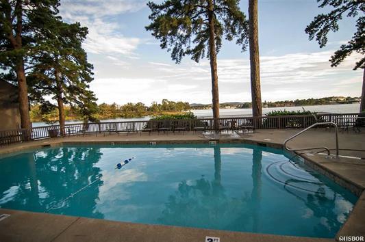 A large swimming pool with a view of a lake surrounded by trees.