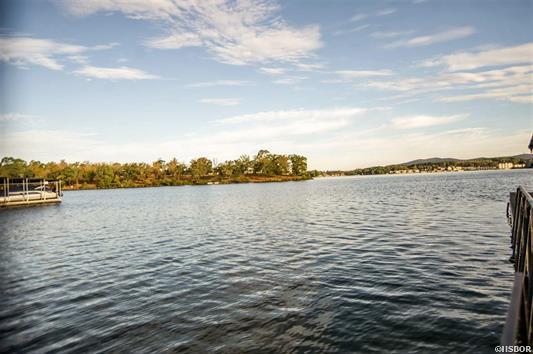 A large body of water with a dock in the foreground and trees in the background.
