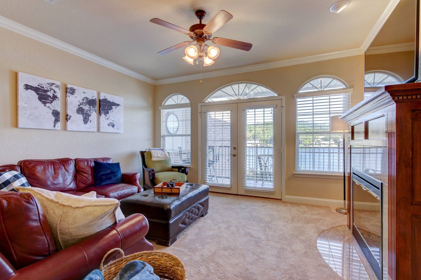 A living room with a couch , chair , coffee table , fireplace and ceiling fan.
