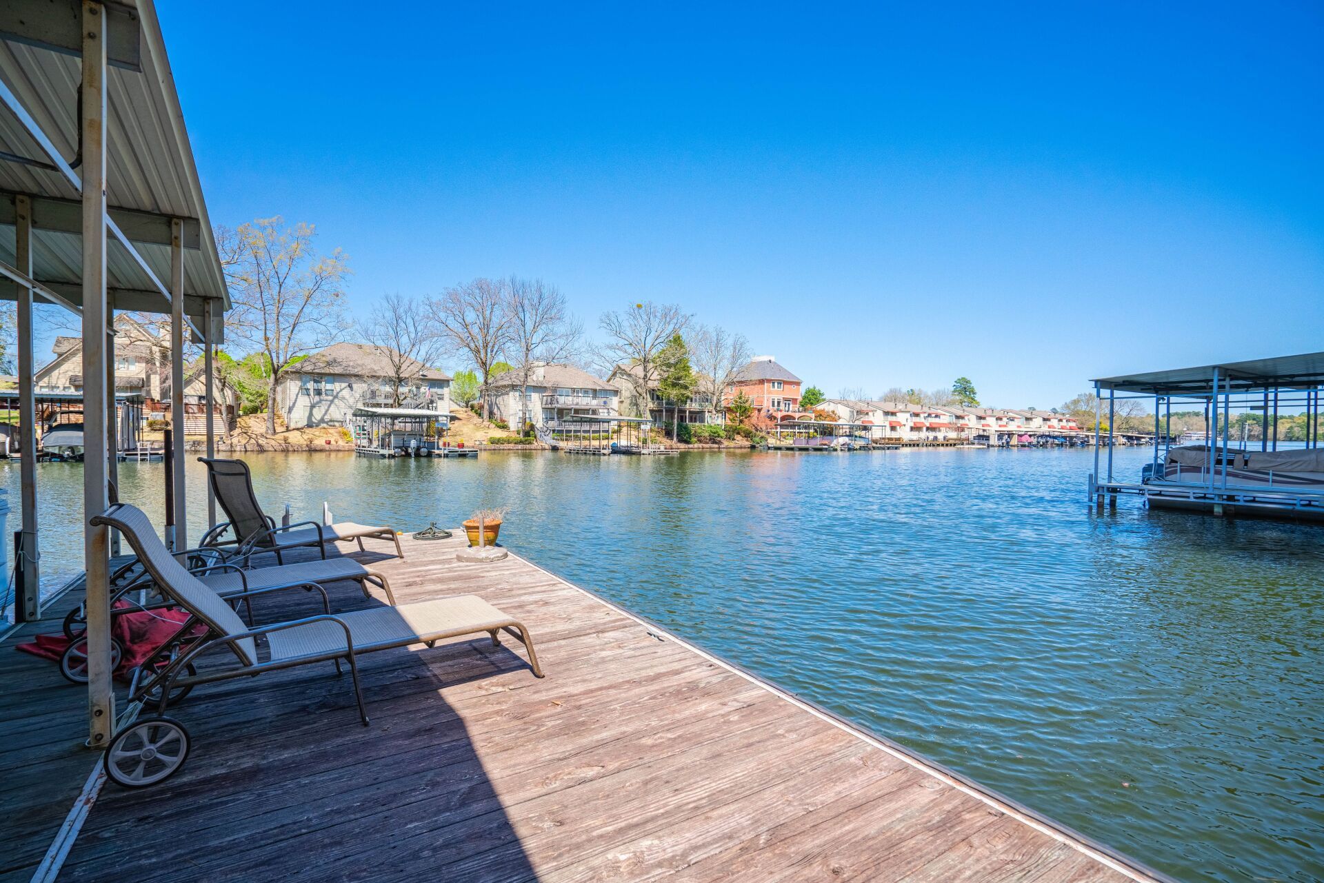 A dock with chairs and a boat docked in the water.