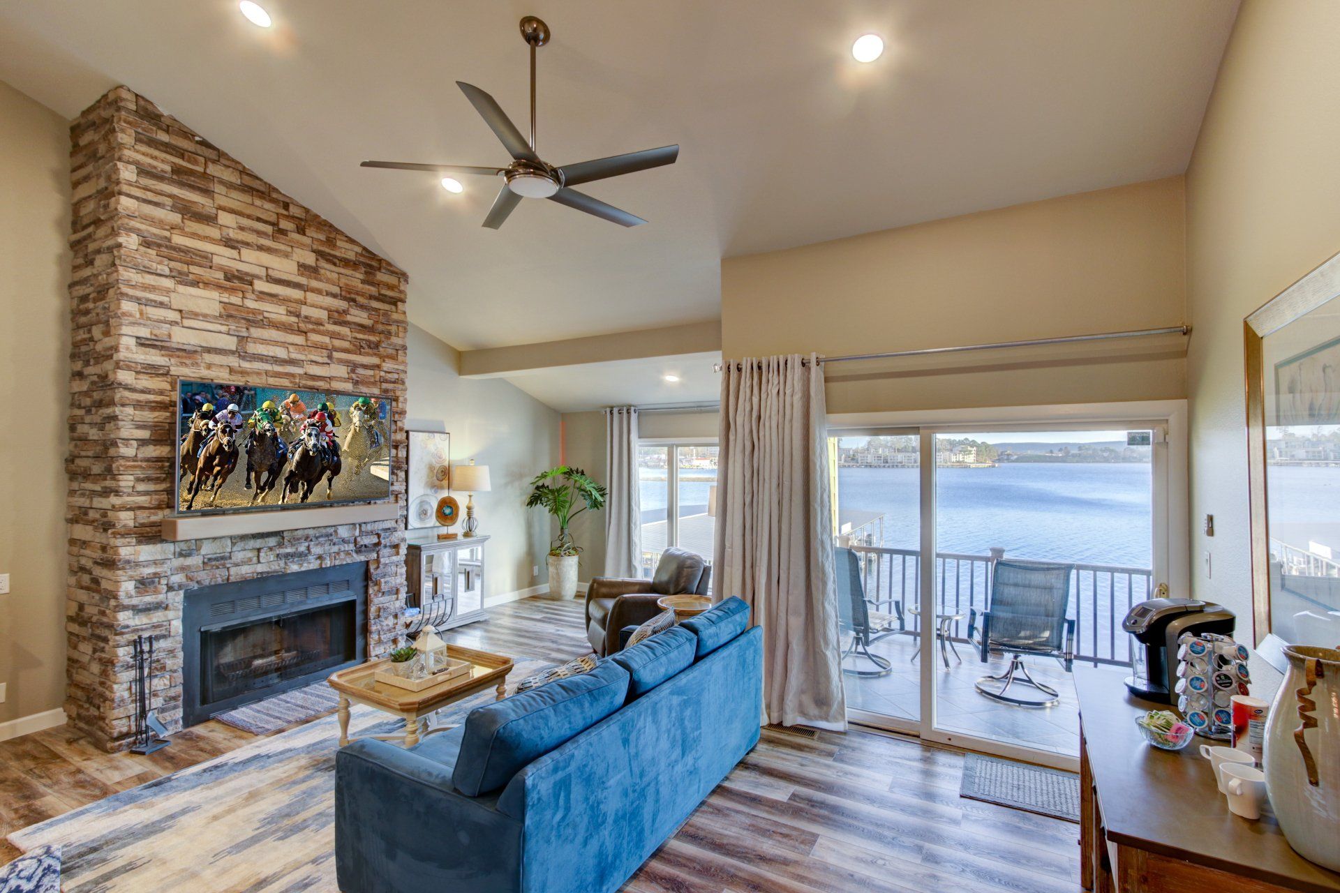 A living room with a blue couch , fireplace and ceiling fan.