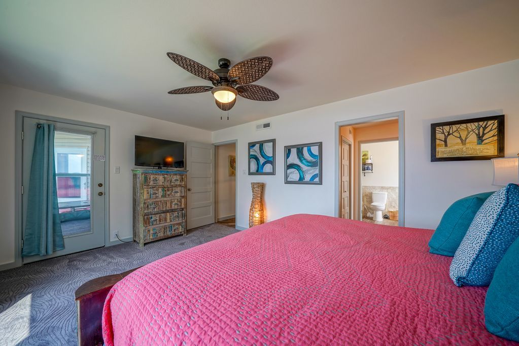 A bedroom with a large bed and a ceiling fan.