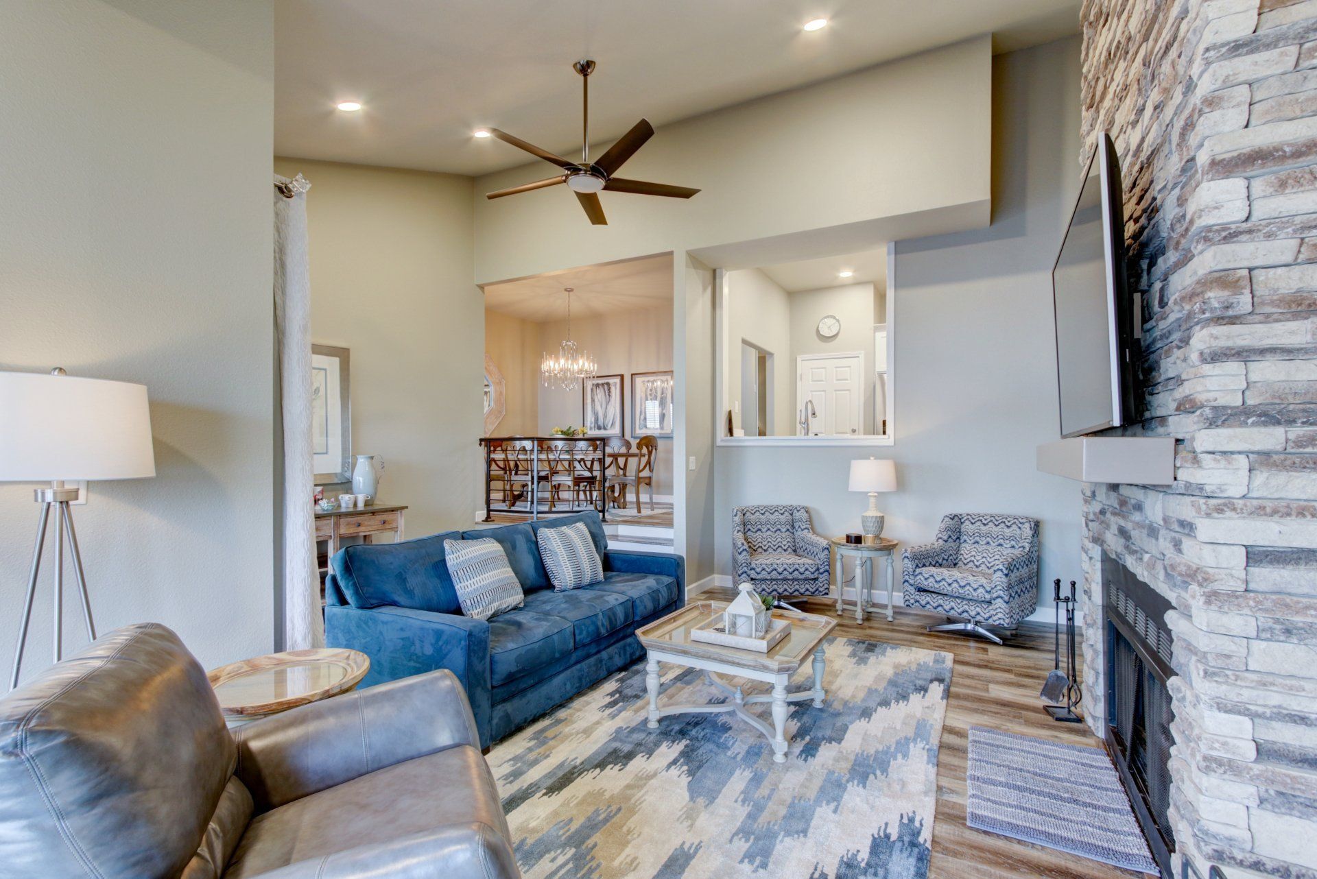 A living room with a couch , chairs , a fireplace and a ceiling fan.