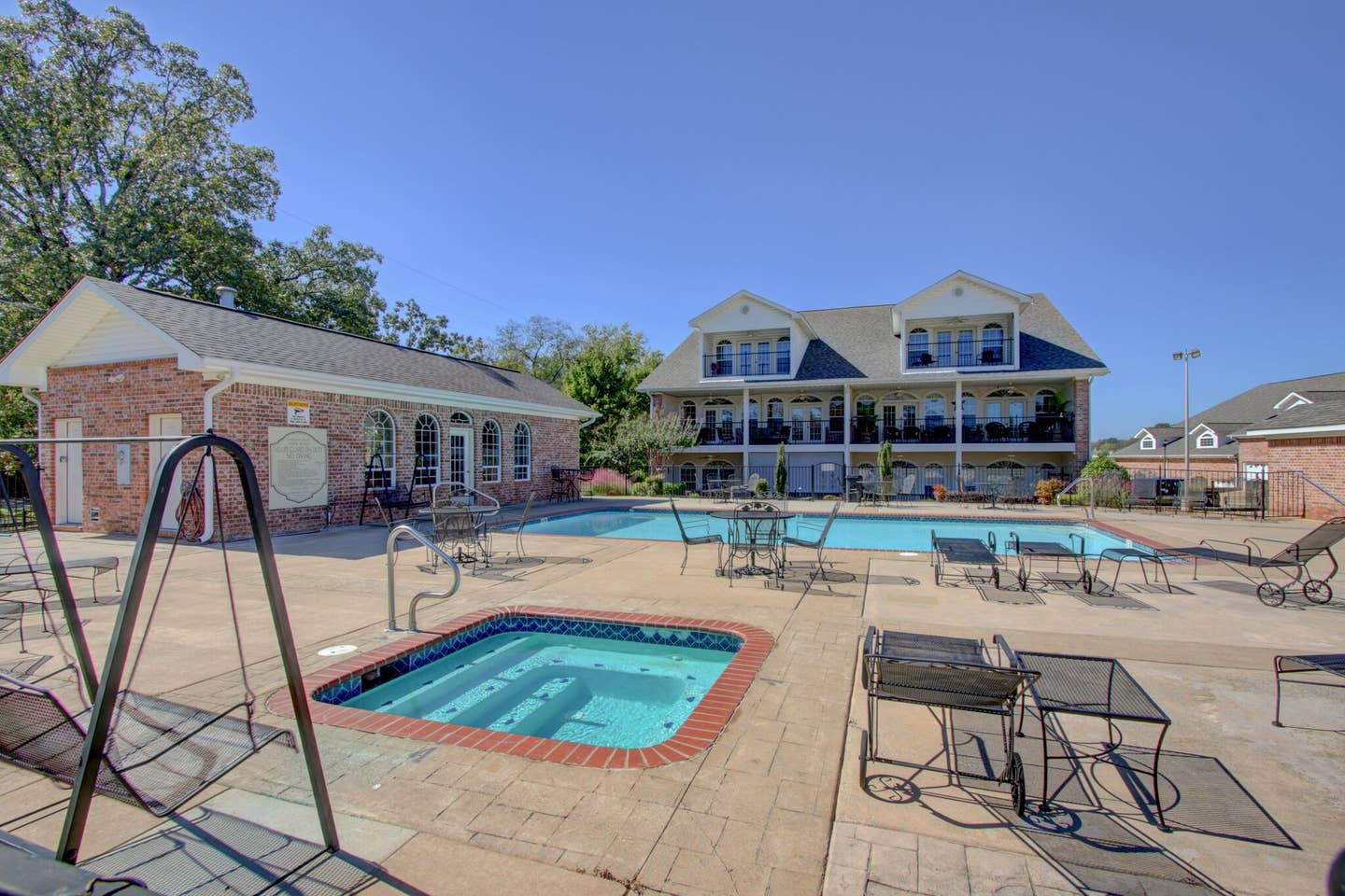 A large house with a swimming pool and a hot tub in front of it.