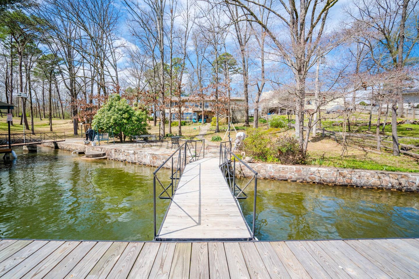 A wooden dock leading to a body of water surrounded by trees.