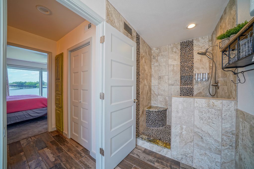 A bathroom with a walk in shower and a closet.