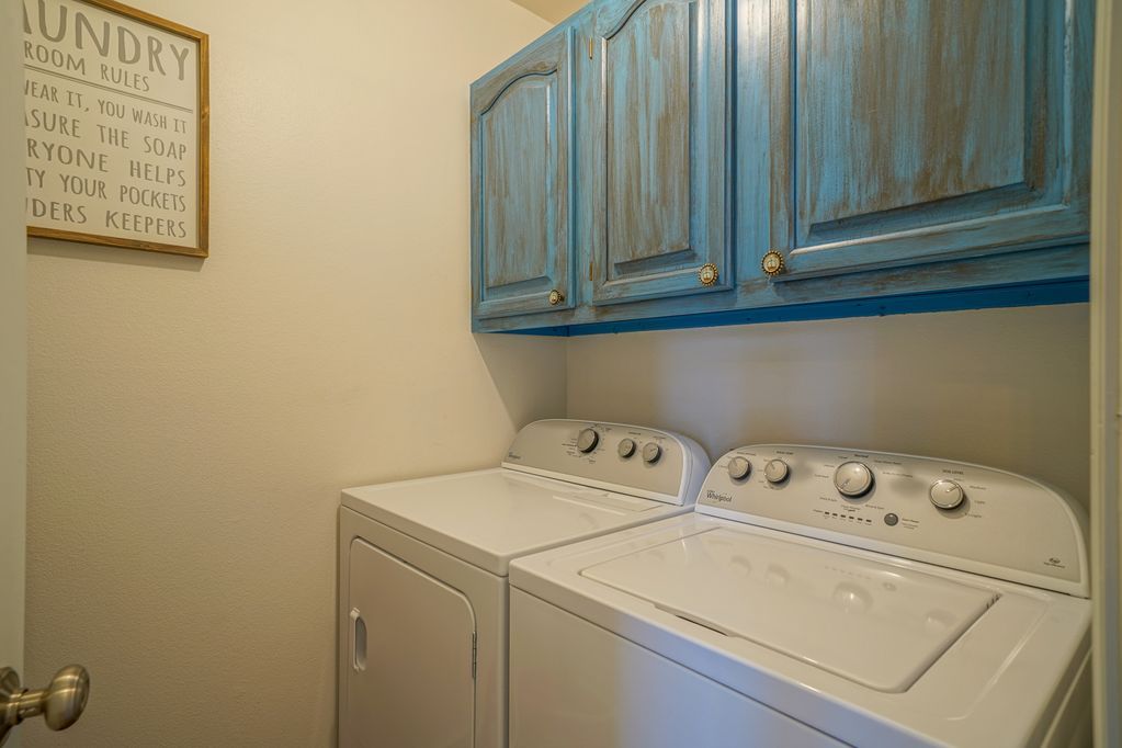 A laundry room with a washer and dryer and blue cabinets.
