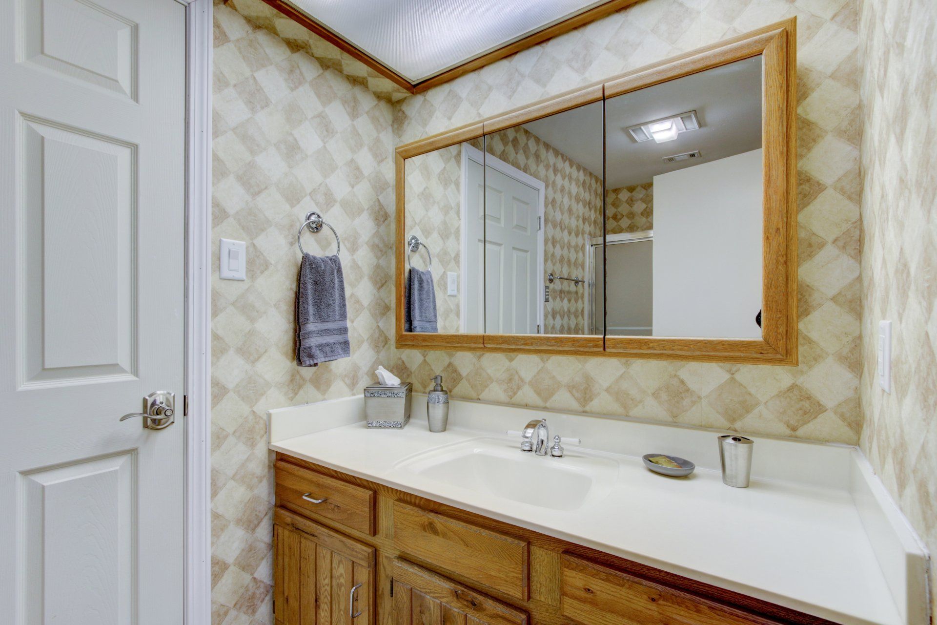 A bathroom with a sink , mirror and cabinets.